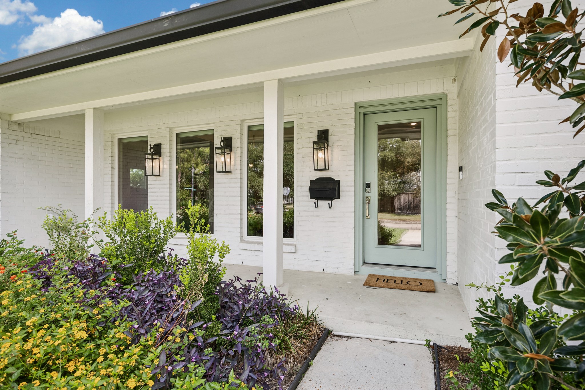 A charming covered front porch welcomes you home, complemented by beautiful landscaping and a soft green front door. Classic exterior details create an inviting first impression.