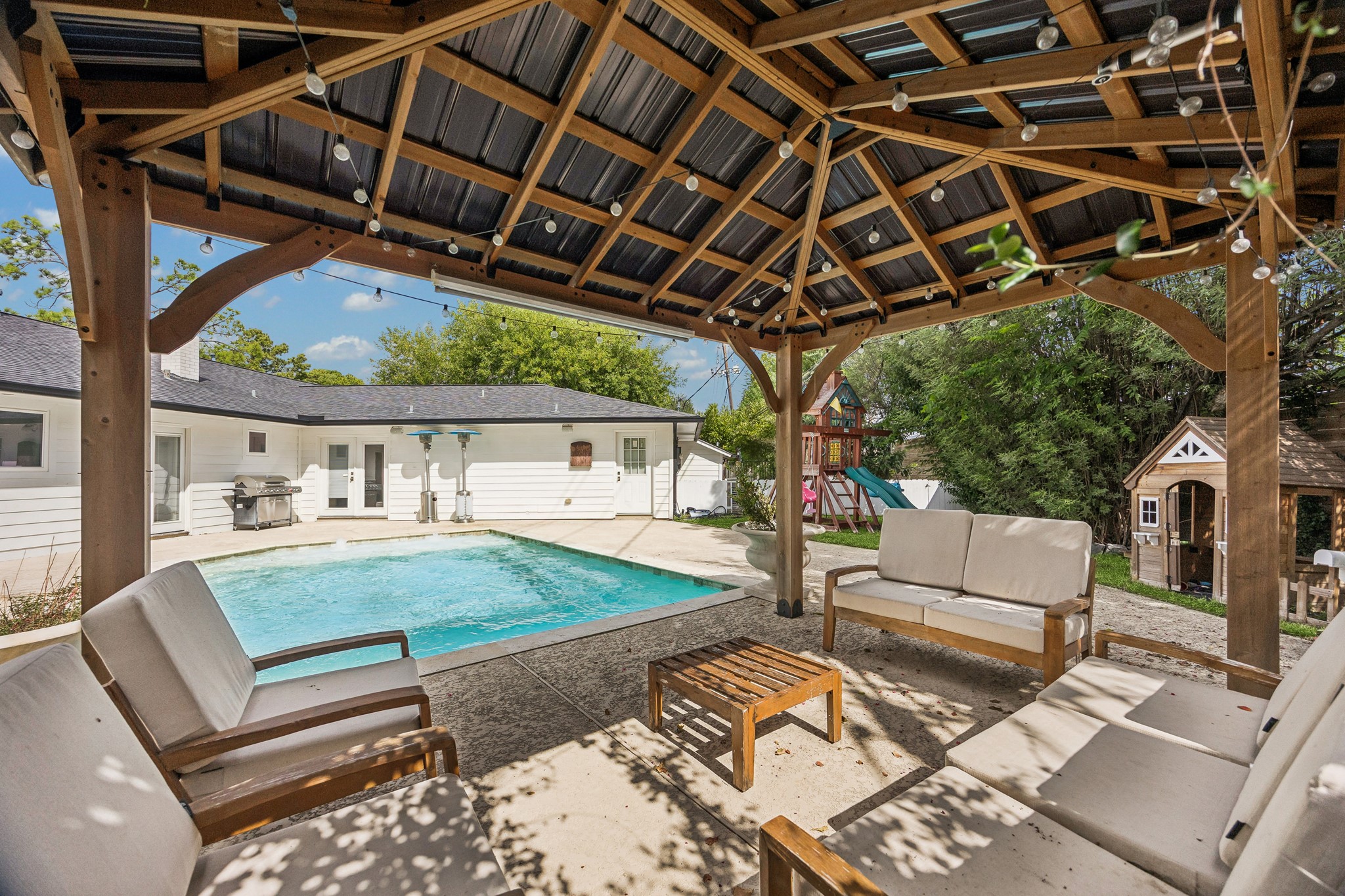 The covered pergola offers a shaded lounge and fire table seating area just steps from the pool. It's an ideal setting for entertaining or unwinding under
the stars.