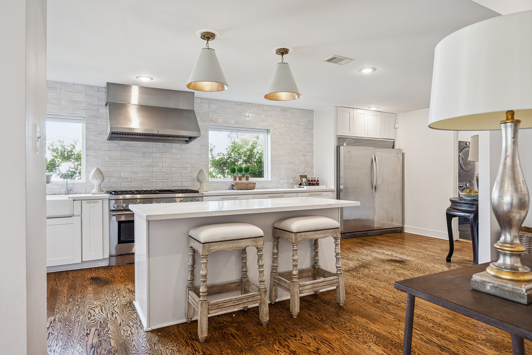 (25x10) This luxurious kitchen includes an apron sink, subway tile backsplash, Whirlpool side by side refrigerator, and an island that adds valuable prep space. Together, they create a layout as functional as it is refined.