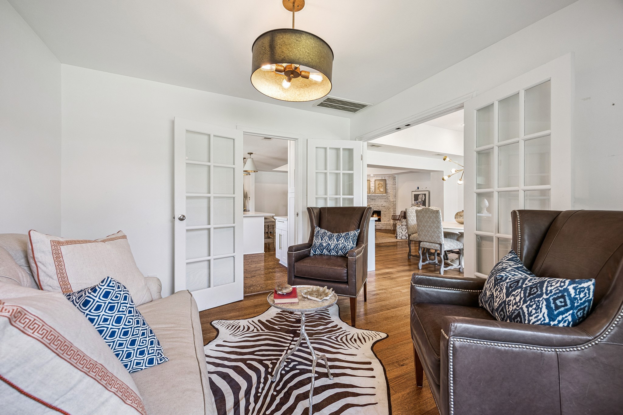 French doors open to a charming sitting room, offering a versatile space for a home office, reading retreat, or additional lounge area. Rich hardwood flooring and a decorative light fixture complete the inviting space.