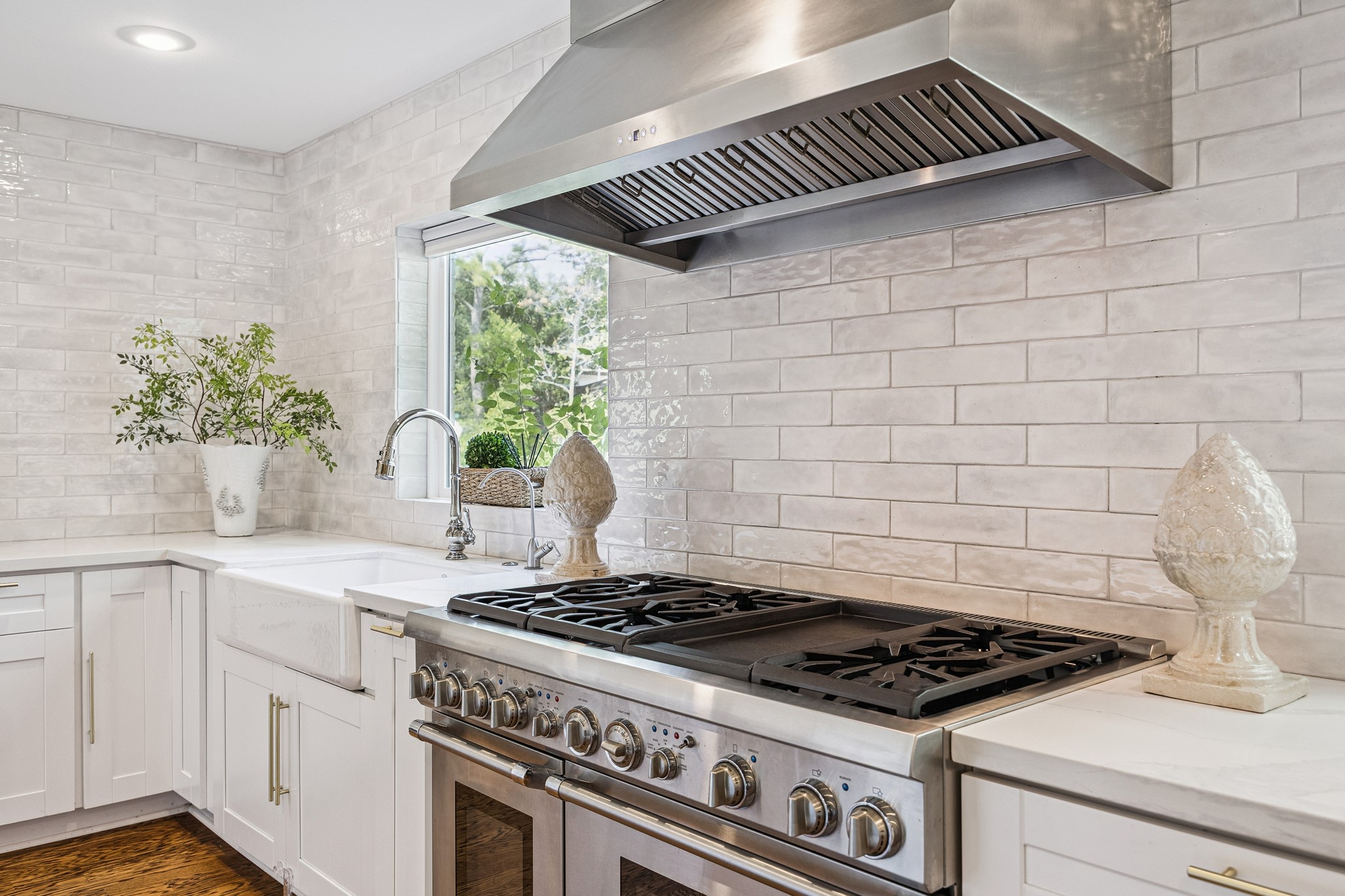 A professional-style Thermador gas range with double ovens anchors this beautifully appointed kitchen. The stainless steel vent hood and elegant tile backsplash add both function and sophistication.