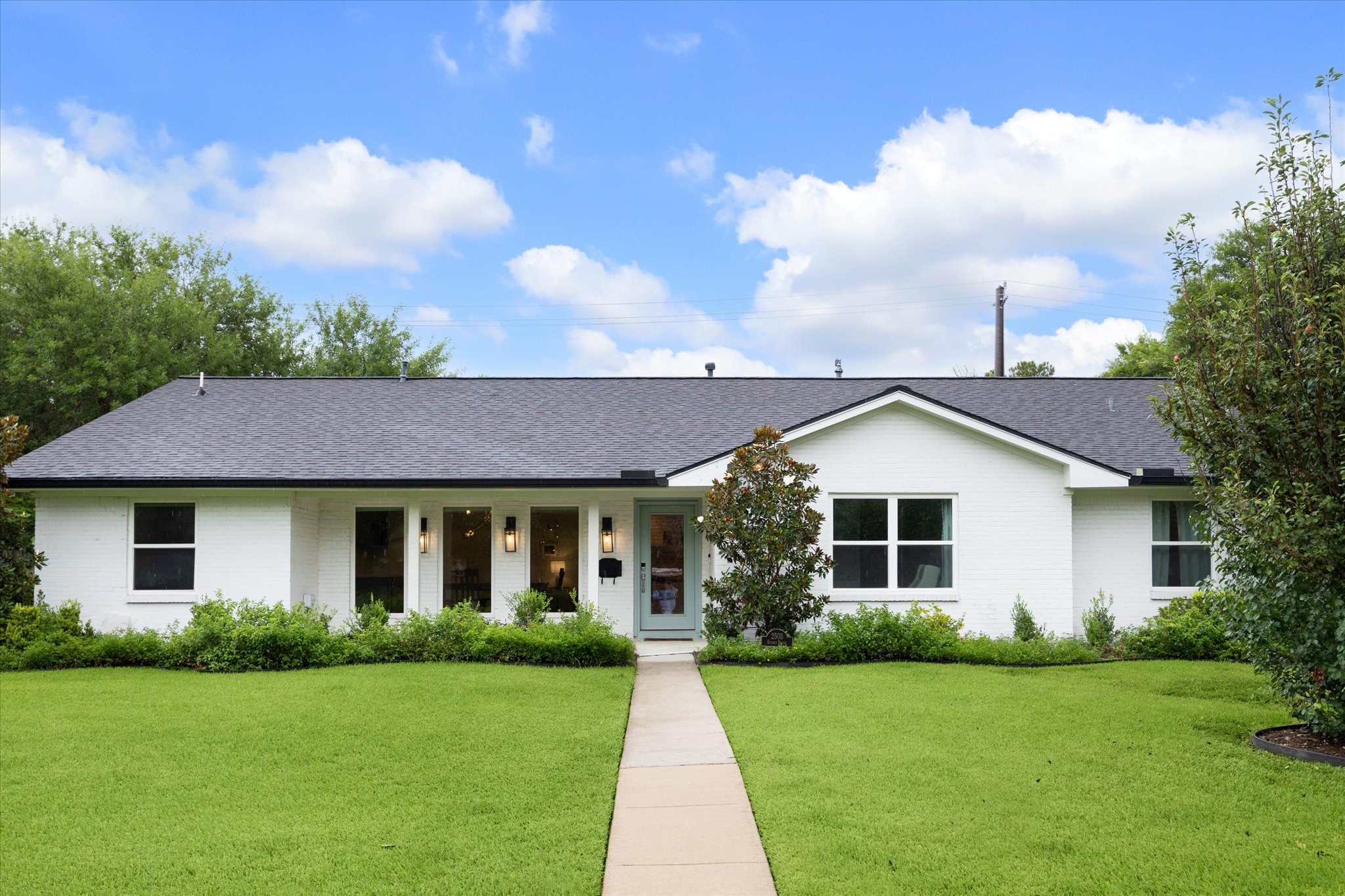 This beautiful white brick residence makes a
striking first impression, framed by a manicured
lawn and mature landscaping. A charming painted front door adds a pop of color against the crisp
faade, setting the tone on this corner lot.