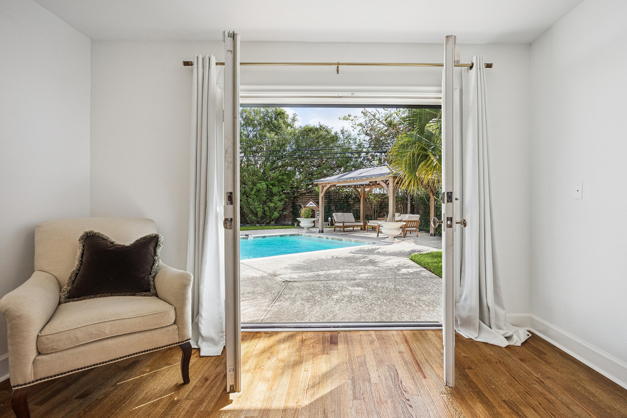 Enjoy convenient access to your private backyard oasis directly from the primary suite. French doors open toward the sparkling pool and covered outdoor pavilion.