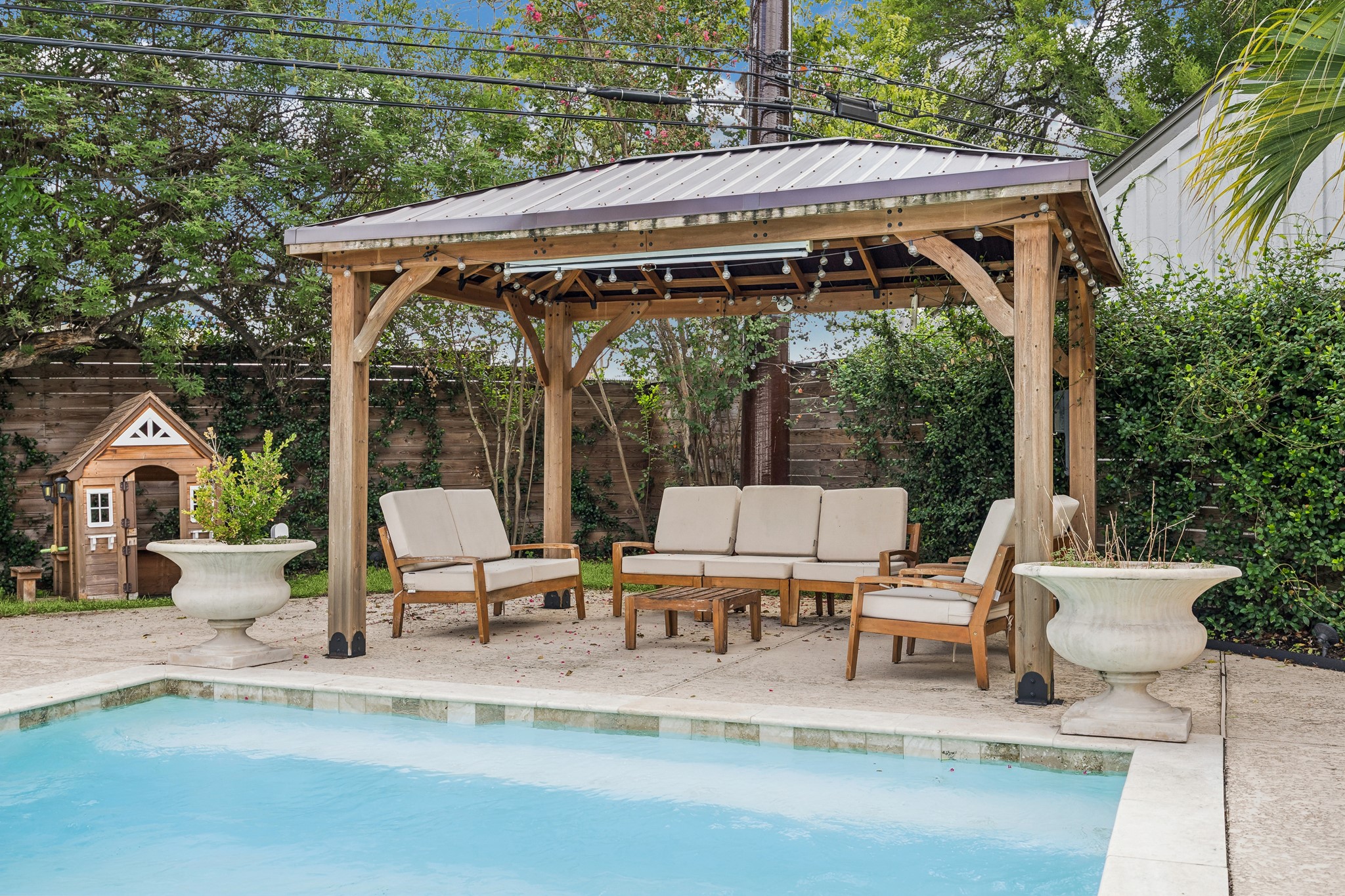 This pergola seating area enjoys sweeping views of the pool beyond, creating a seamless connection between shaded lounging and outdoor recreation.
The space is designed for effortless indoor-outdoor entertaining.