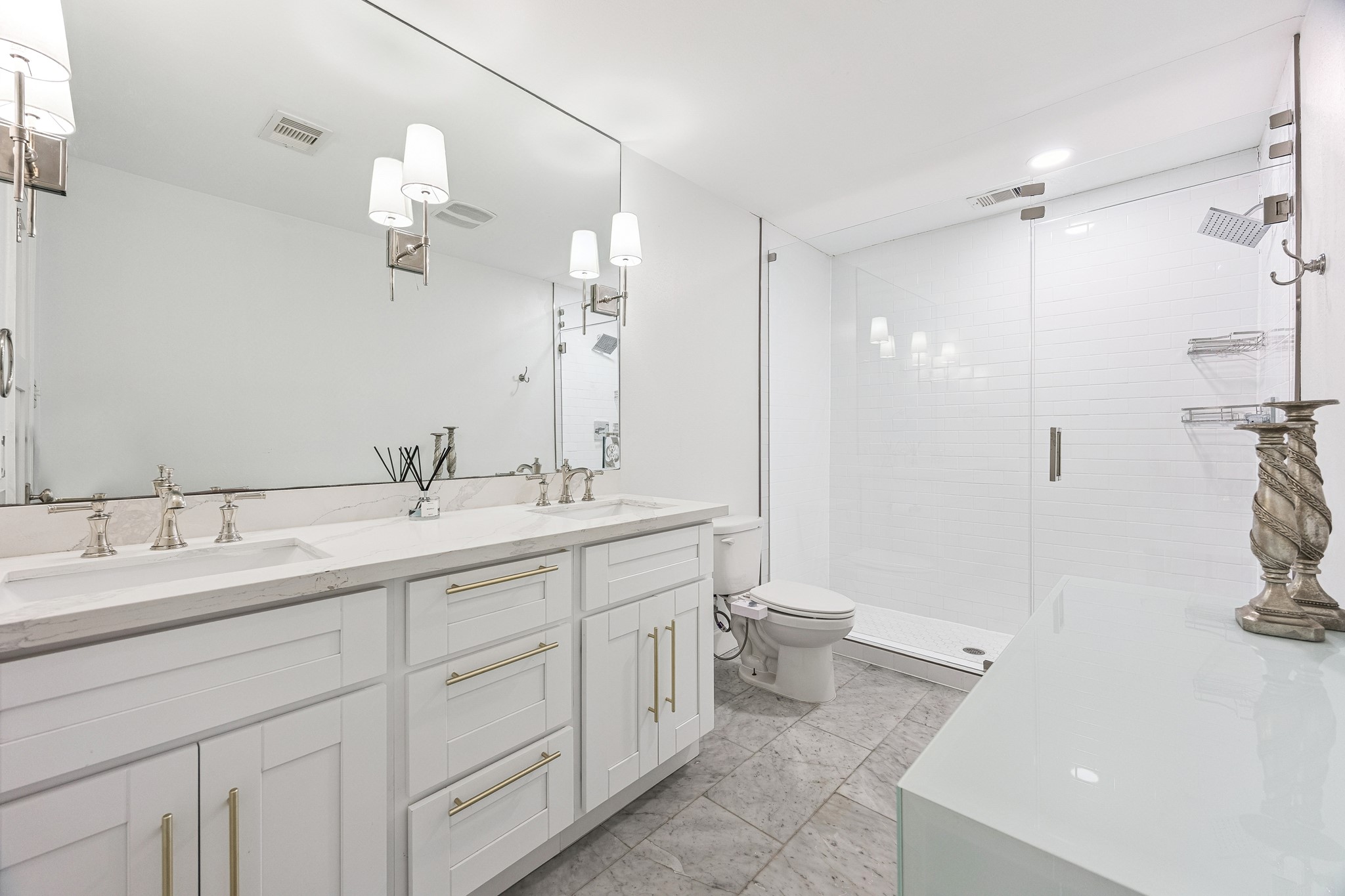 This spa-inspired bath features dual vanities paired with a frameless glass shower, offering both function and refined style. Clean lines and quality finishes come together for an elevated everyday routine.