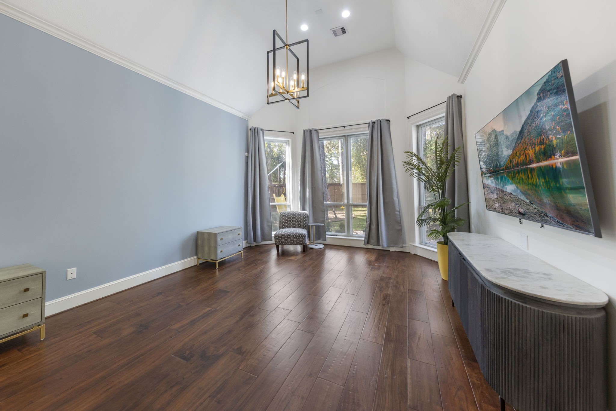 Spacious primary suite boasts high vaulted ceilings, bay window, and beautiful wood floors.