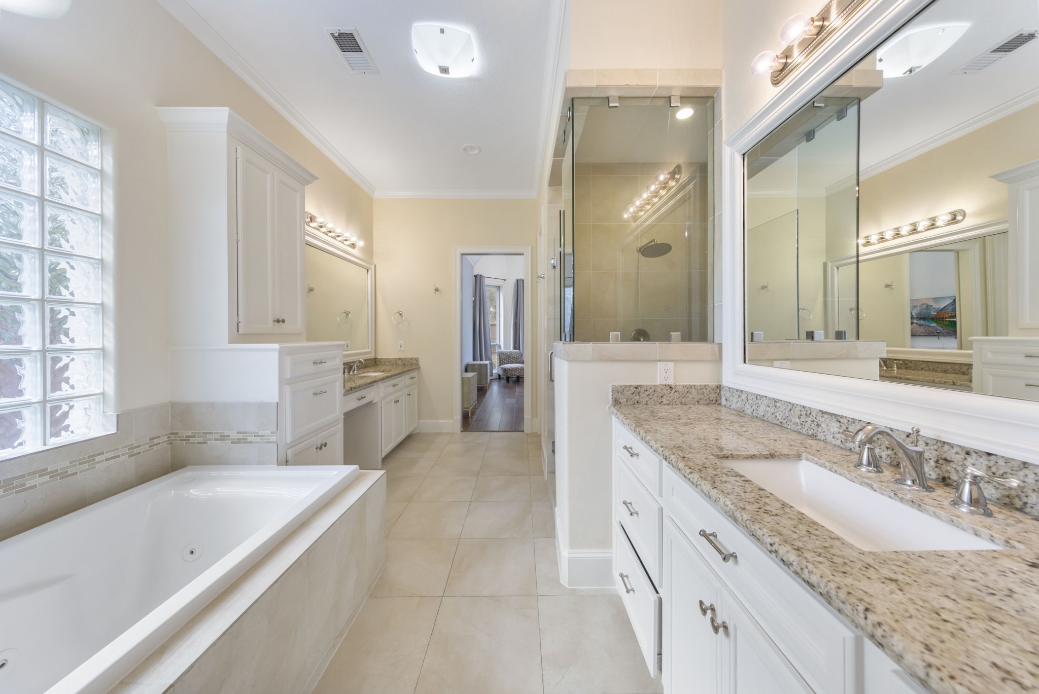The primary bath provides a spacious retreat, featuring an oversized walk-in shower, a luxurious soaking tub, and dual sinks with a convenient vanity seating area.