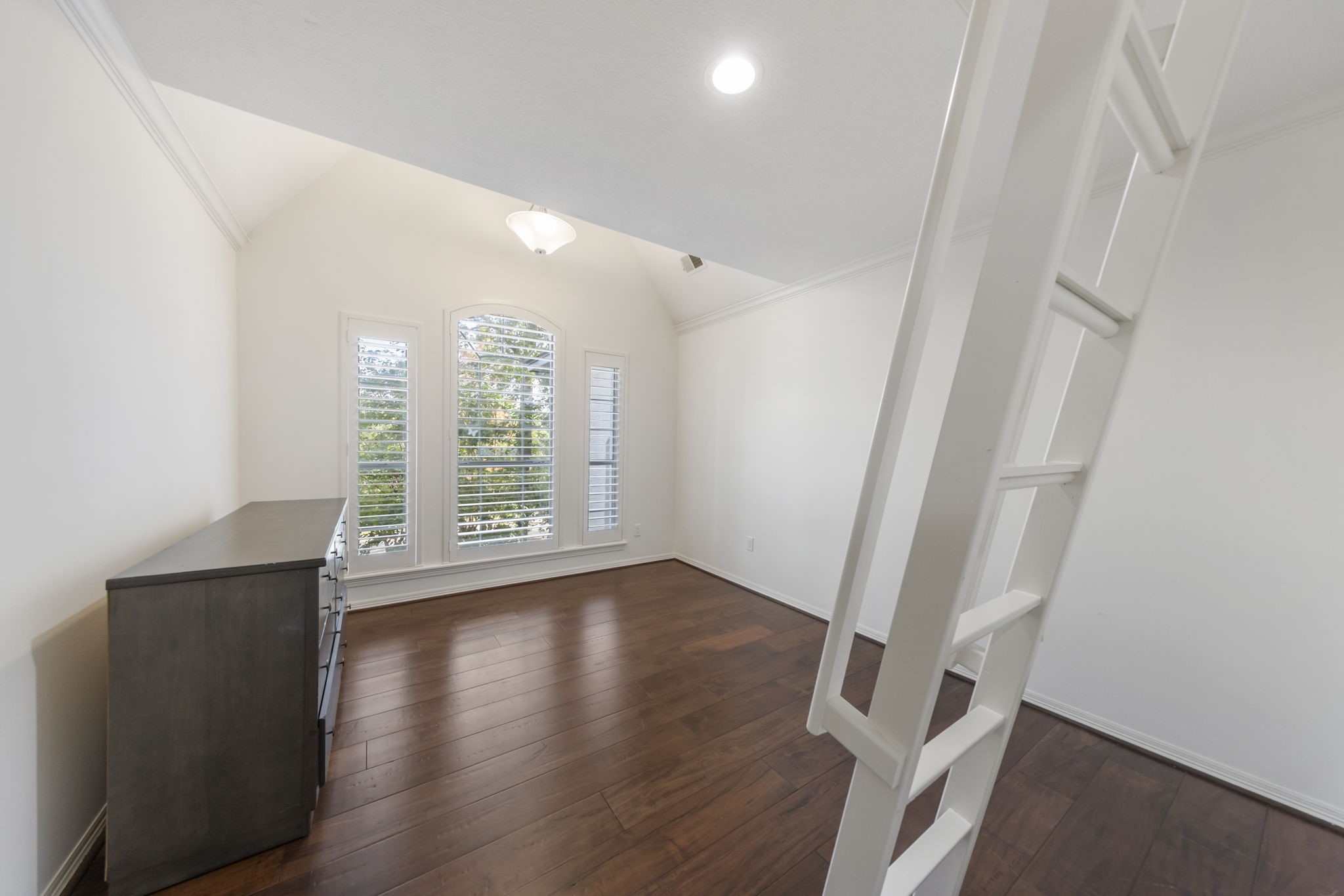 This additional upstairs bedroom features a high A-frame ceiling and a charming loft with ladder access, perfect for a cozy reading nook or a kids' hideaway!