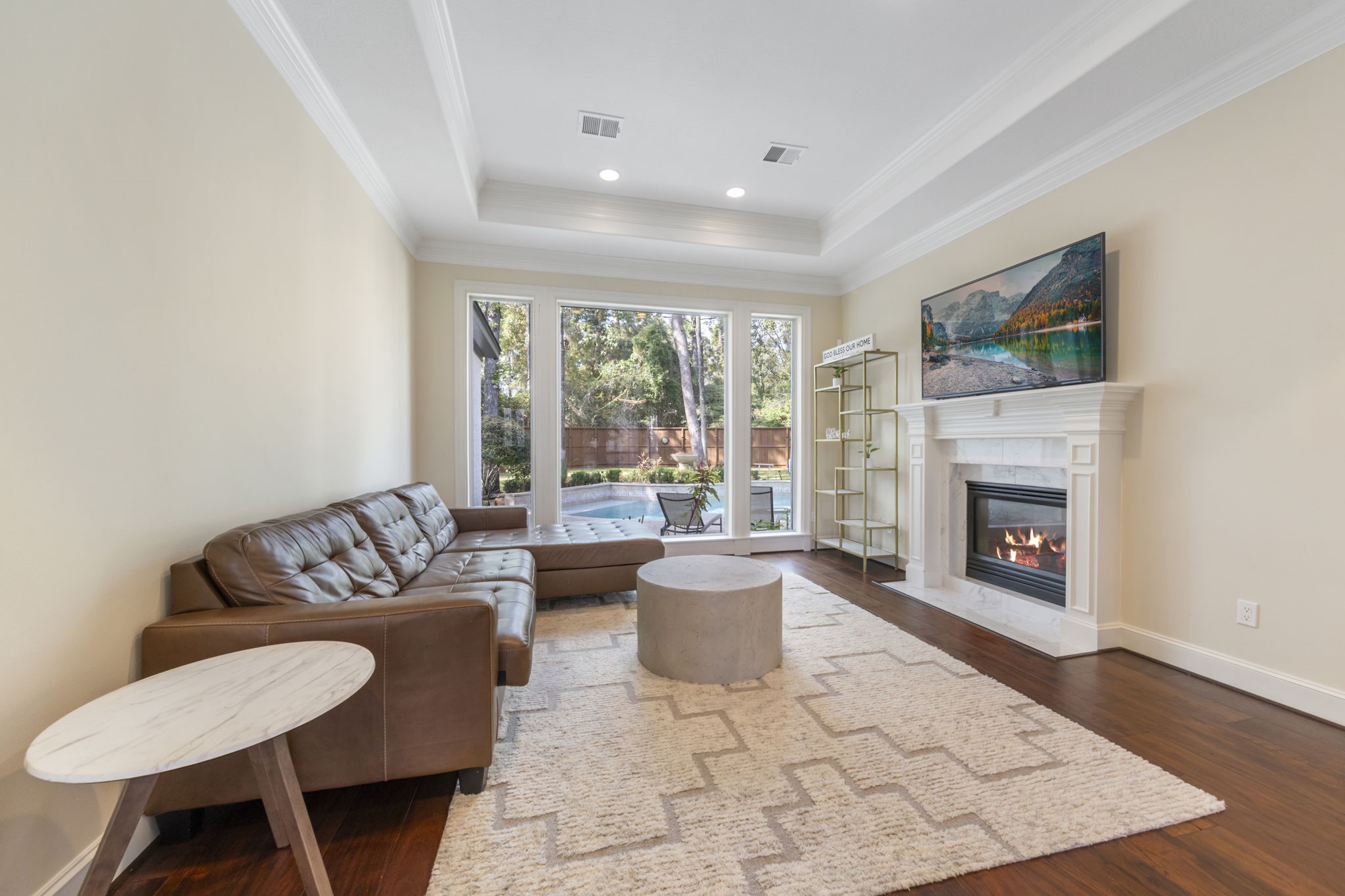 Den situated off formal dining features tray ceiling, cozy fireplace and wall of windows offering ample natural light.