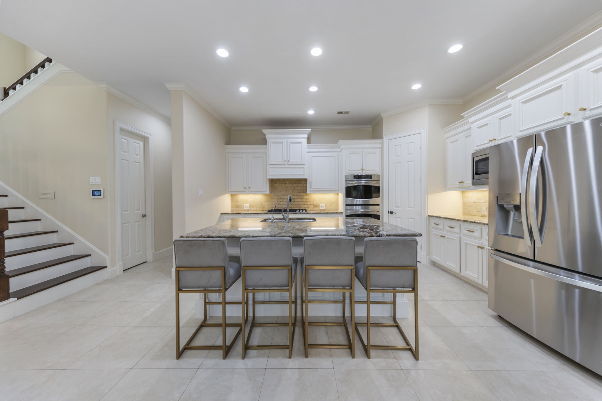 Spacious kitchen offers granite counter tops, oversized island with additional seating, two walk-in pantries, and generous amount of storage space. Back staircase offers easy access to the kitchen.