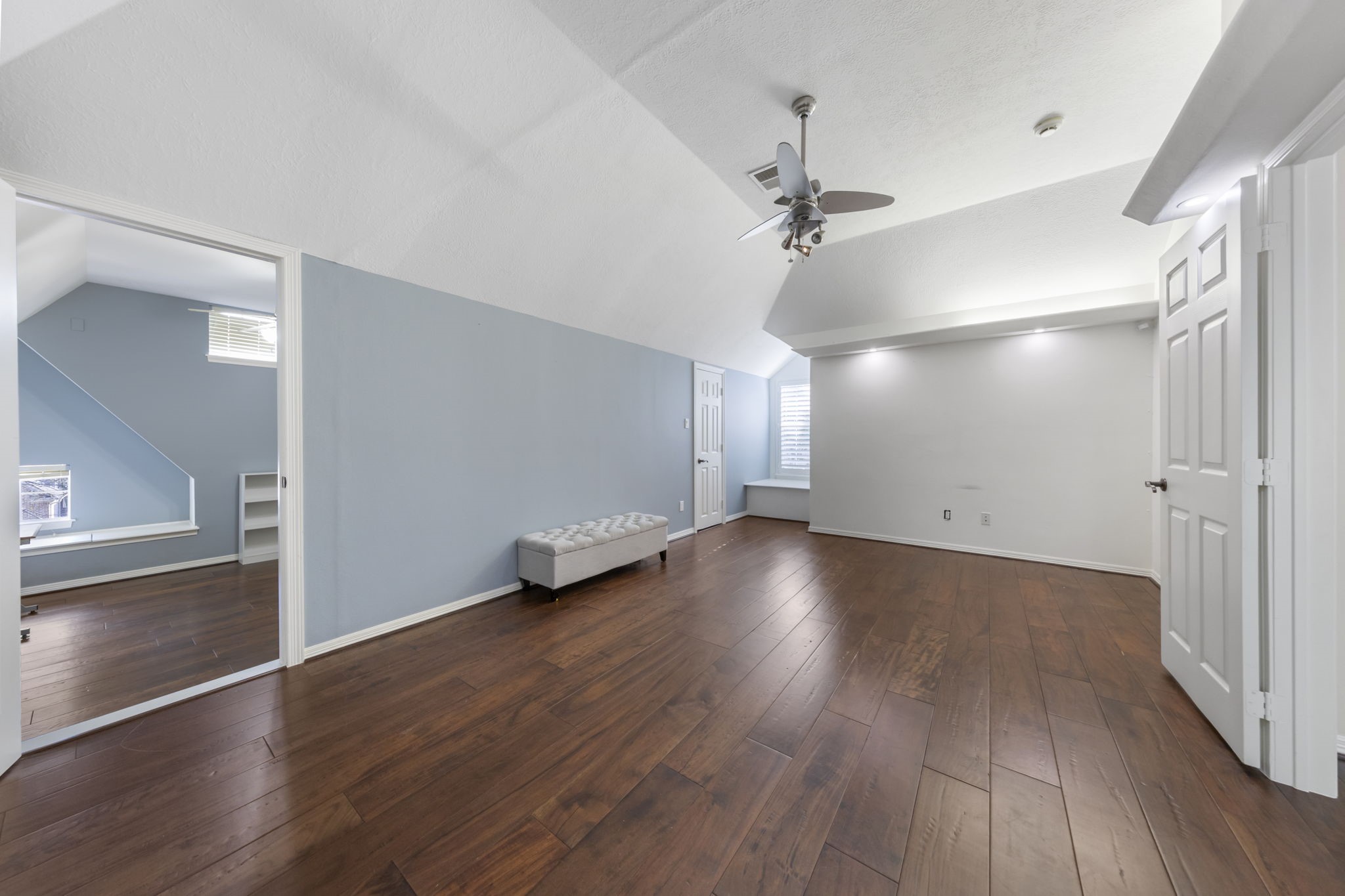 The largest upstairs bedroom showcases wood floors, vaulted ceilings, a cozy window nook, built-in shelves, and an attached hidden room!