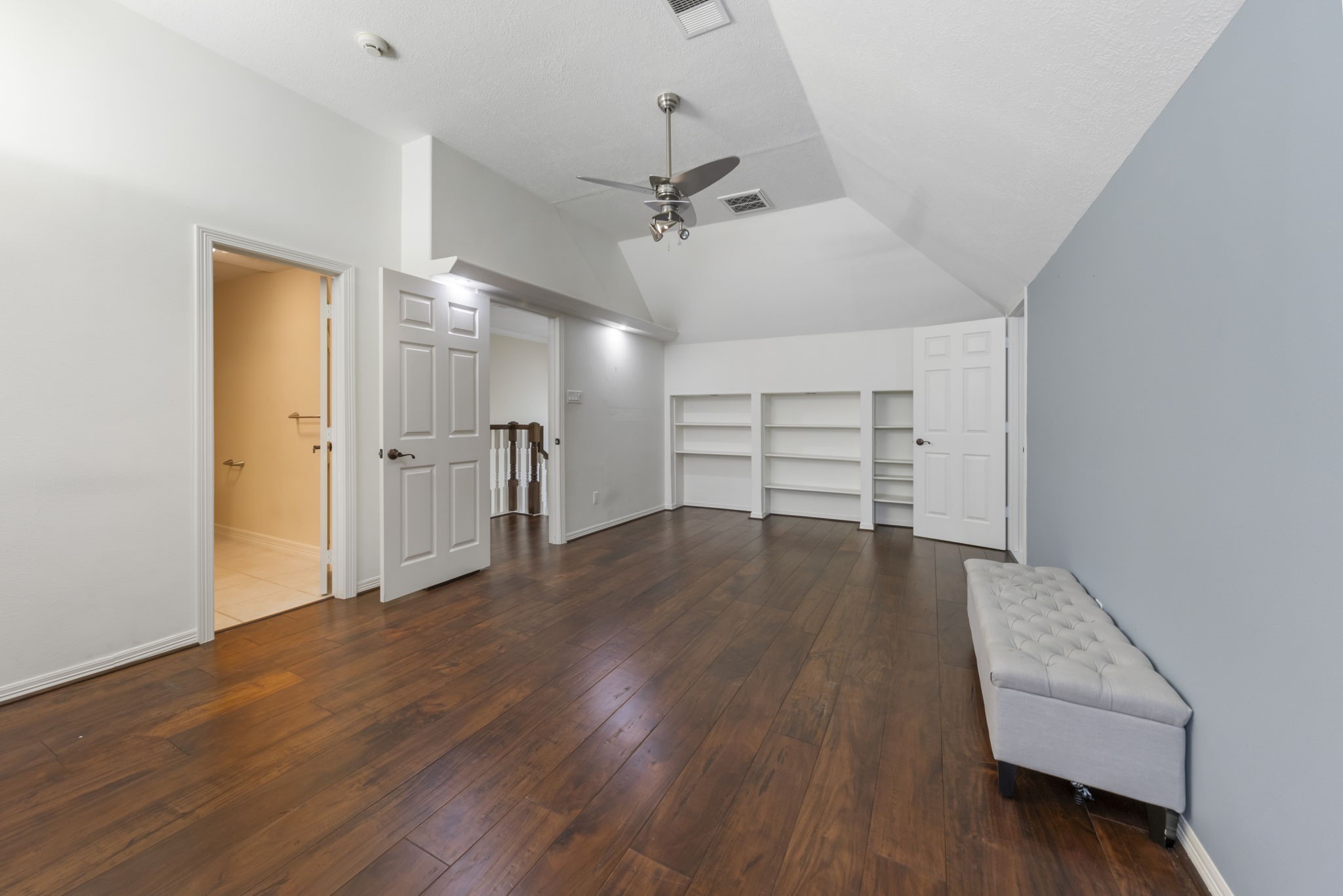 View of spacious upstairs bedroom features ensuite bath, built-in shelves, and access to hidden room!