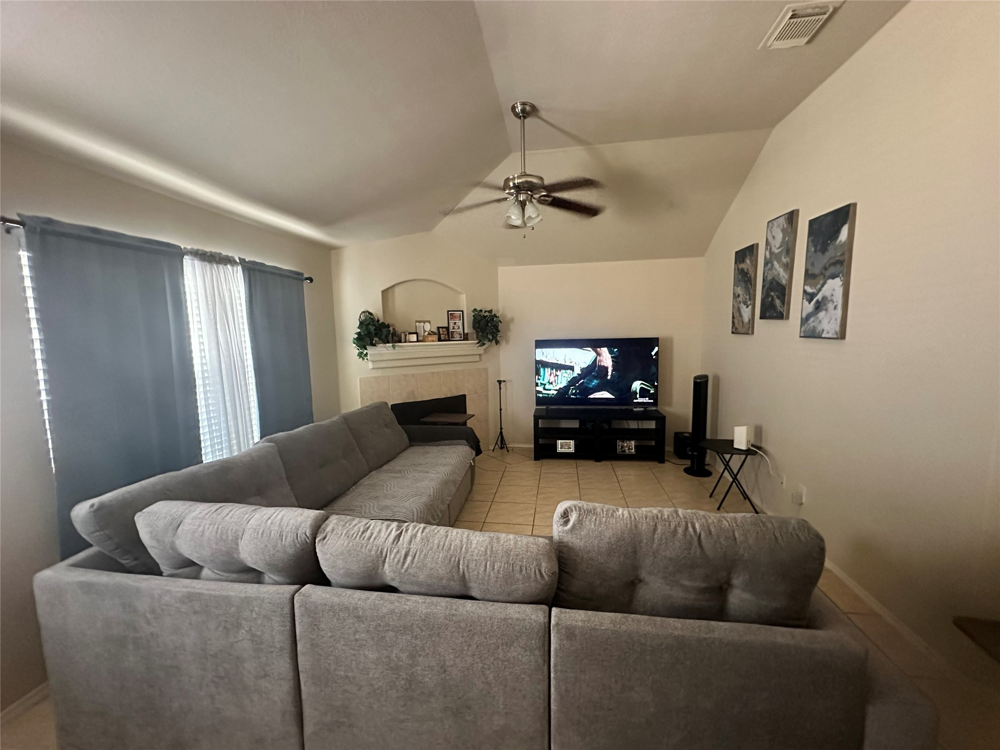 Spacious living room with vaulted ceilings, featuring a cozy gray sectional and a media setup, perfect for relaxation and entertainment.