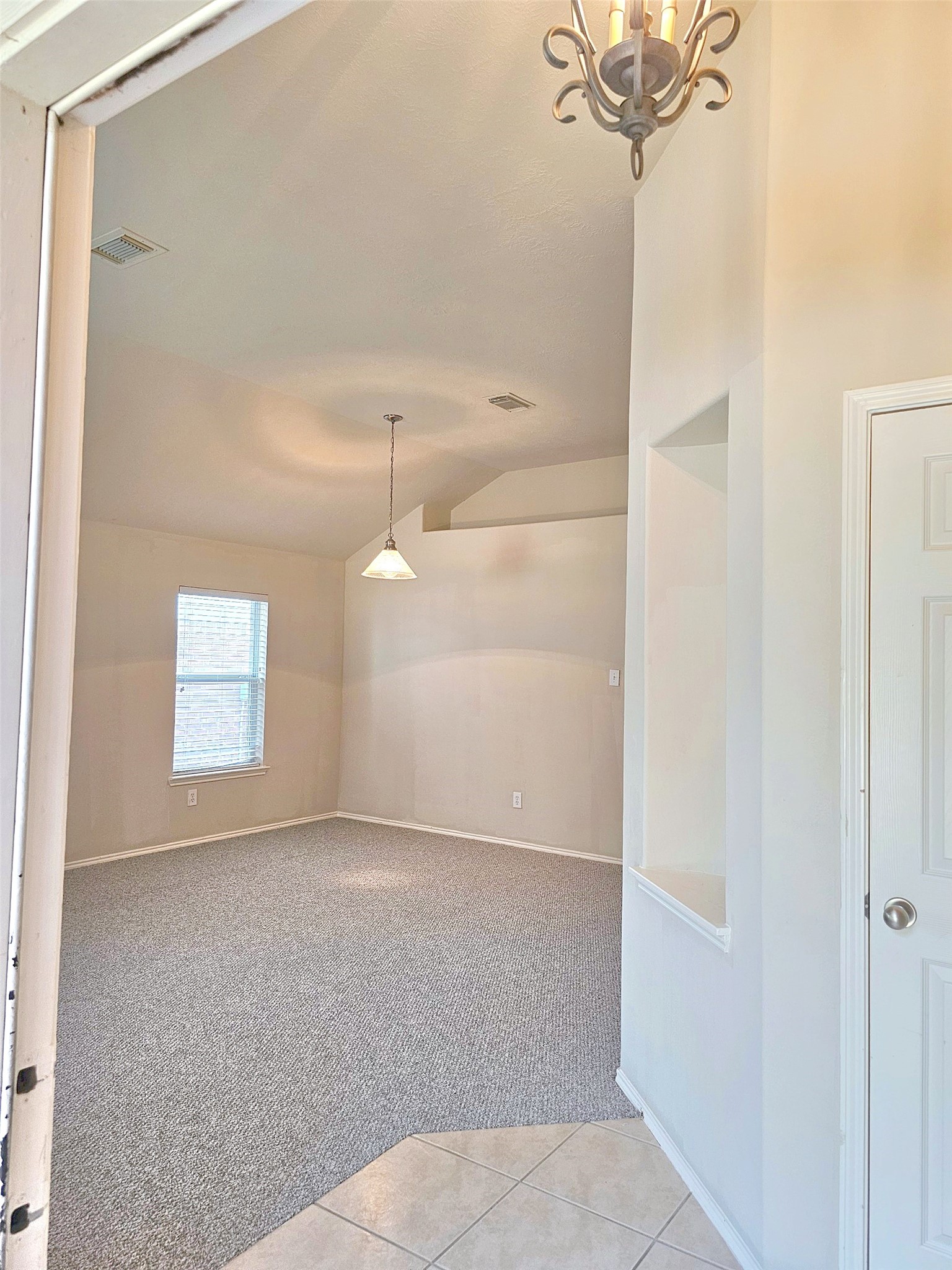 Bright and spacious room with vaulted ceilings, soft carpeting, and elegant lighting, creating a welcoming atmosphere.