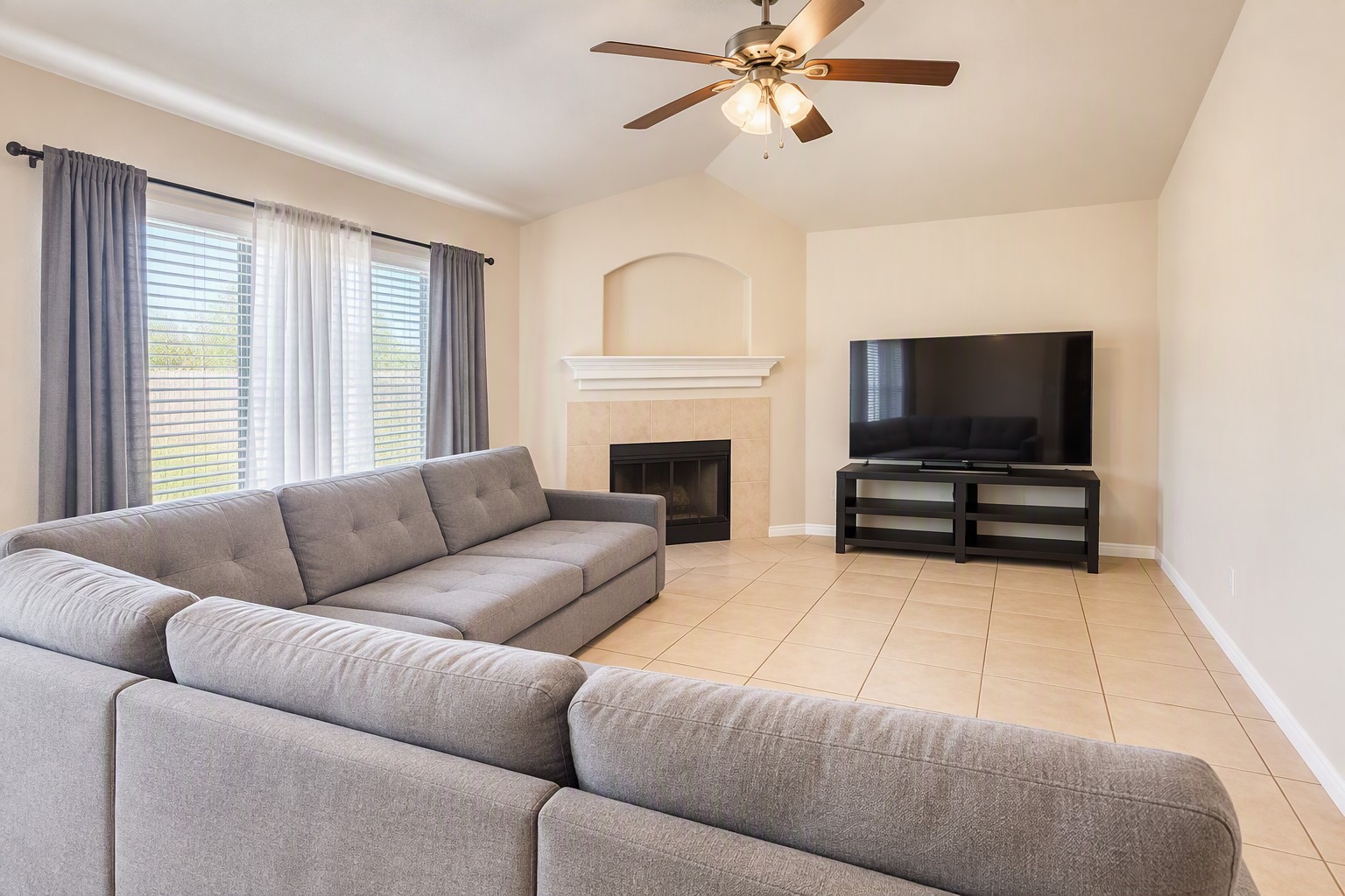 Spacious living room with a cozy fireplace, large sectional sofa, and high ceilings, perfect for relaxing or entertaining.