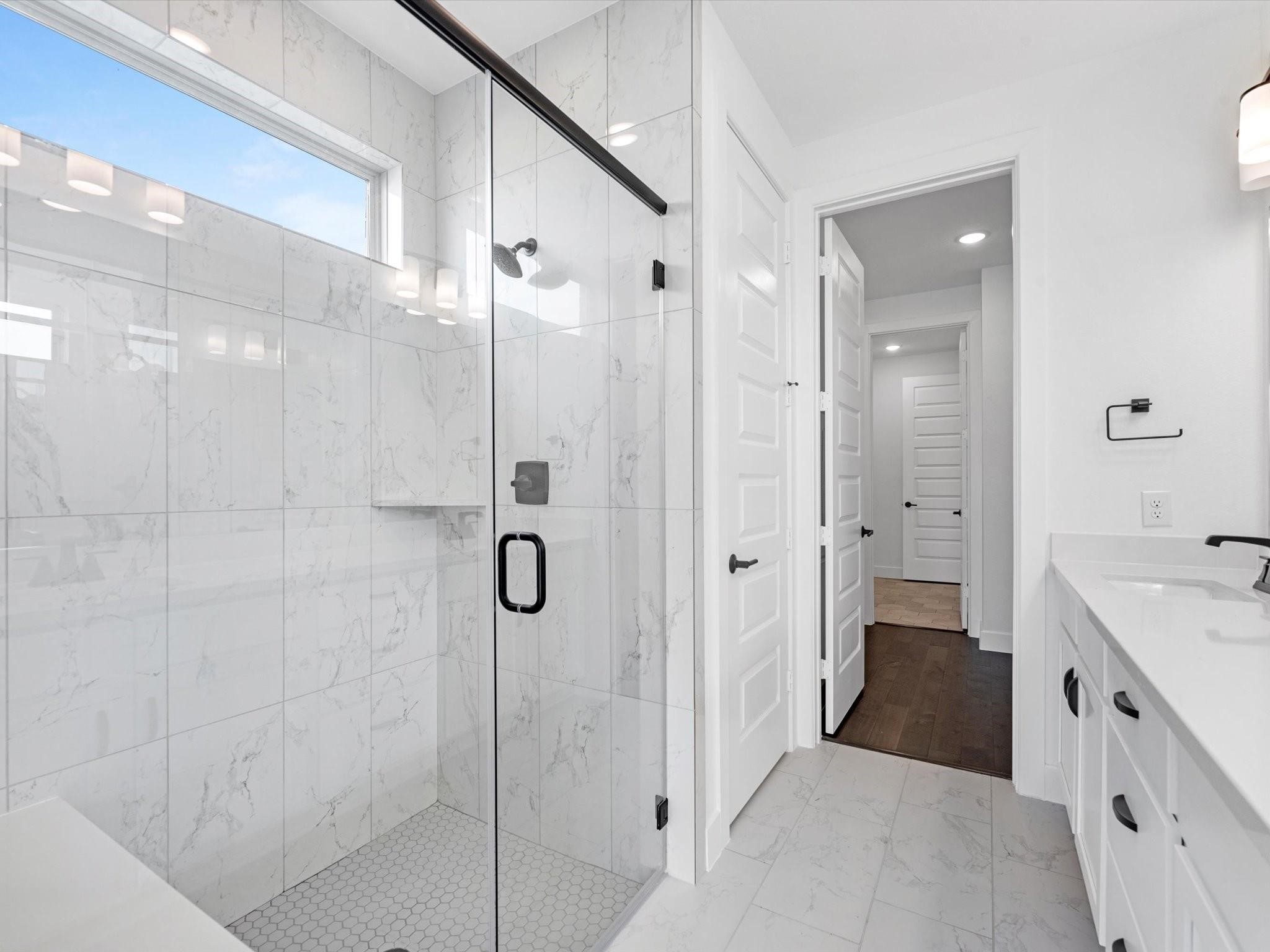A master full bath with stunning white tile seamlessly connects to a wood-accented walk-in closet, which leads directly to the laundry room. Imagine how convenient it is for the owners whenever they need to wash, dry, or fold their laundry.