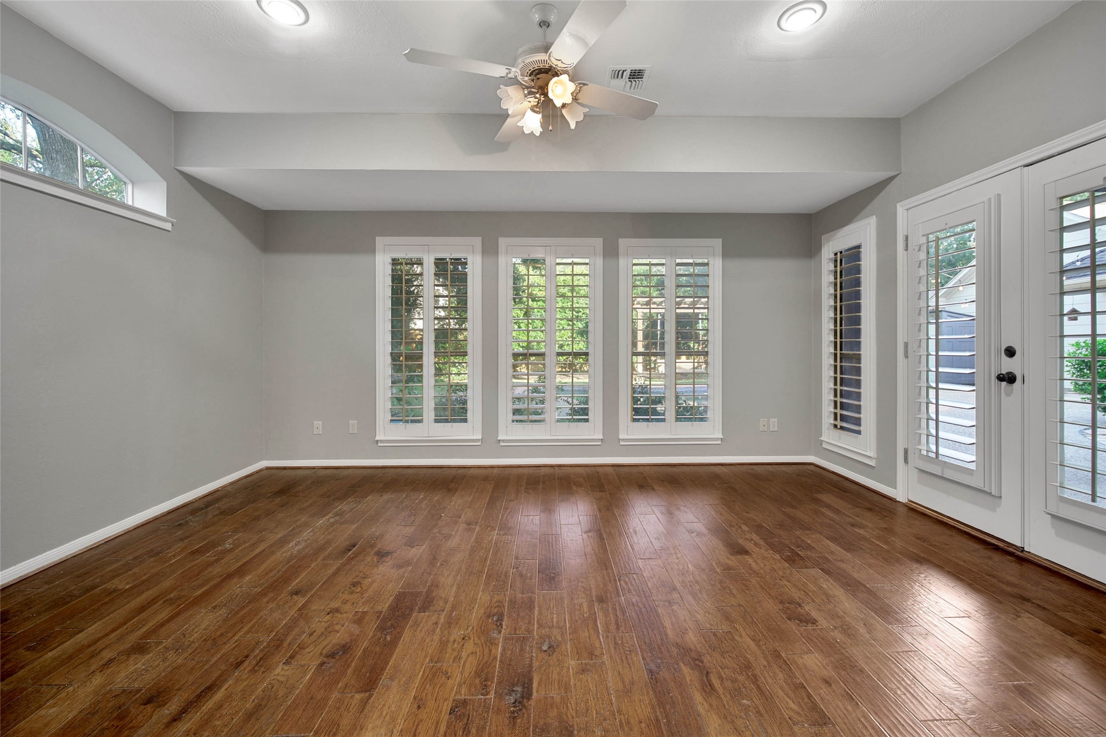 Flex room off the primary has lots of windows and french door access to the patio. Plantation shutters on the windows make this room elegant and also private.