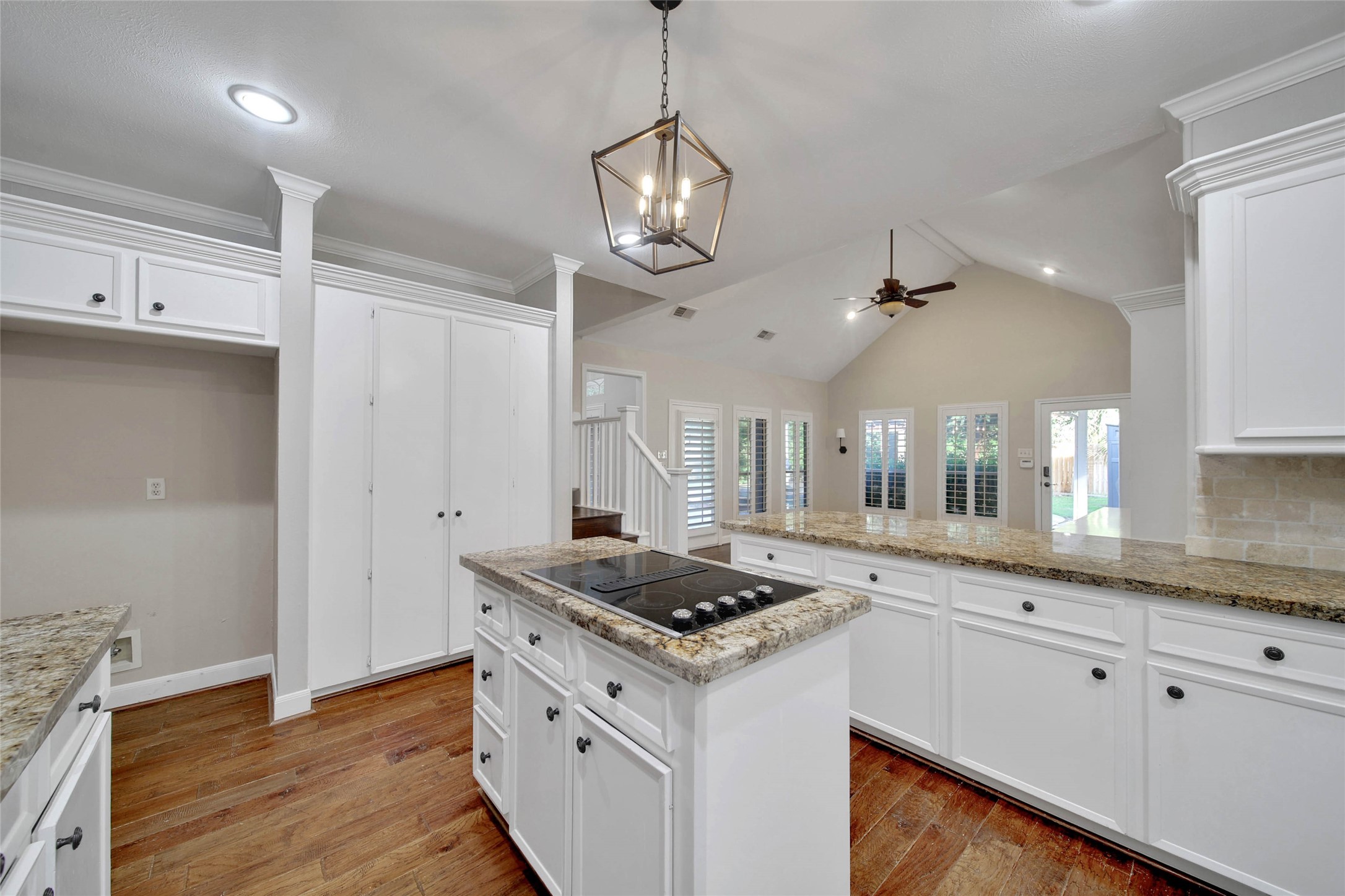 The gorgeous hardwood floors stand out in the kitchen. The kitchen features granite counters, travertine subway tile backsplash, and recessed lighting. The hardwood flooring is carried up the staircase to the second floor.
