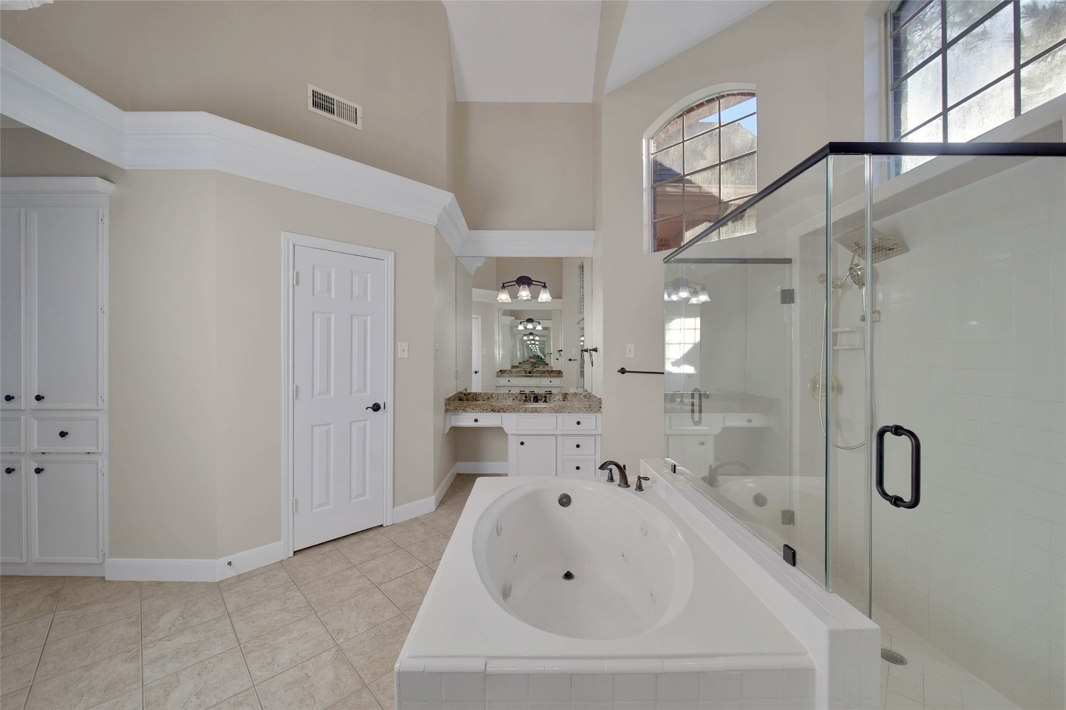Separate whirlpool tub huge oversize shower with two doors, high ceilings and bright windows up high, separate vanities and lots of storage make this a fabulous bathroom.