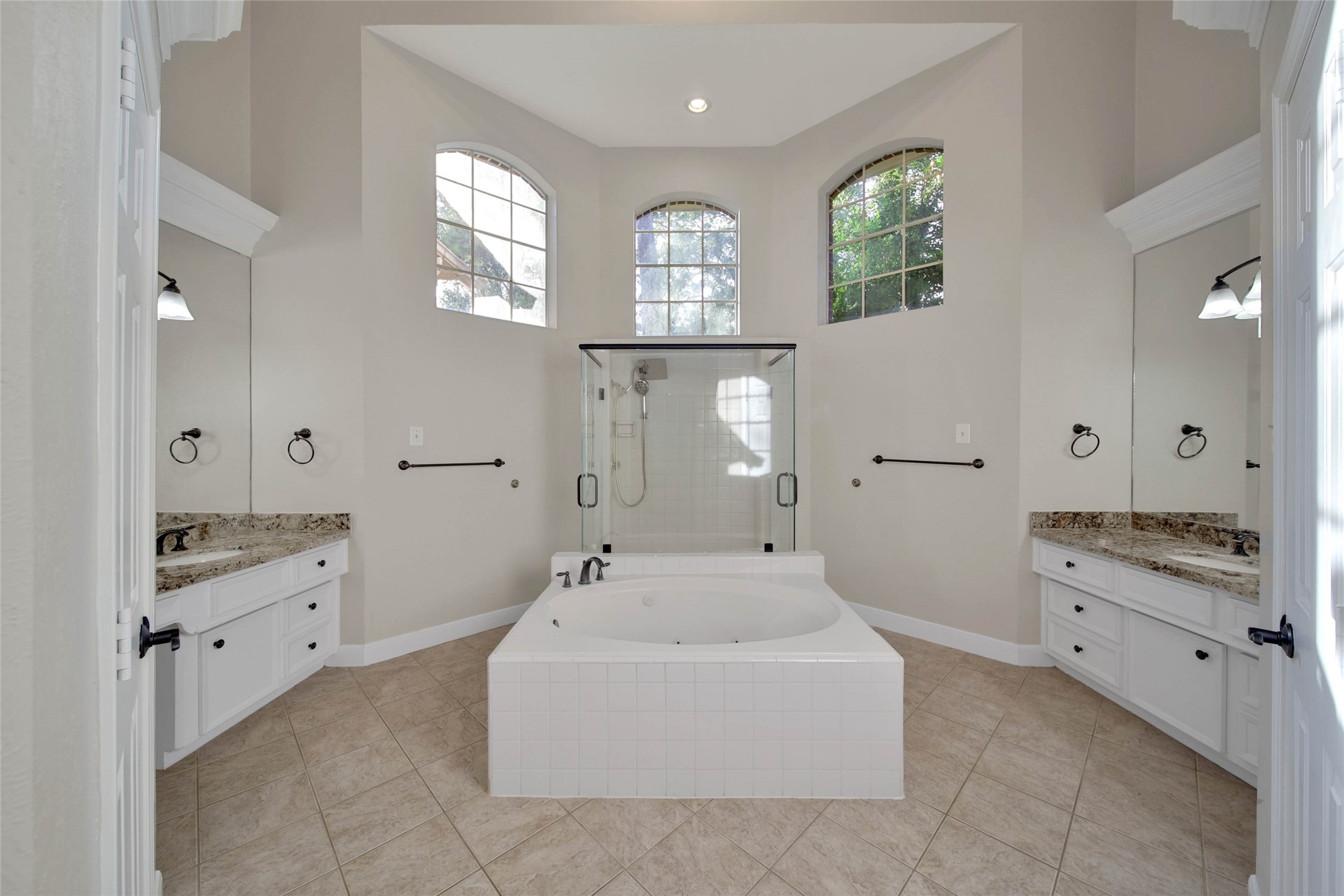 Separate whirlpool tub huge oversize shower with two doors, high ceilings and bright windows up high, separate vanities and lots of storage make this a fabulous bathroom.