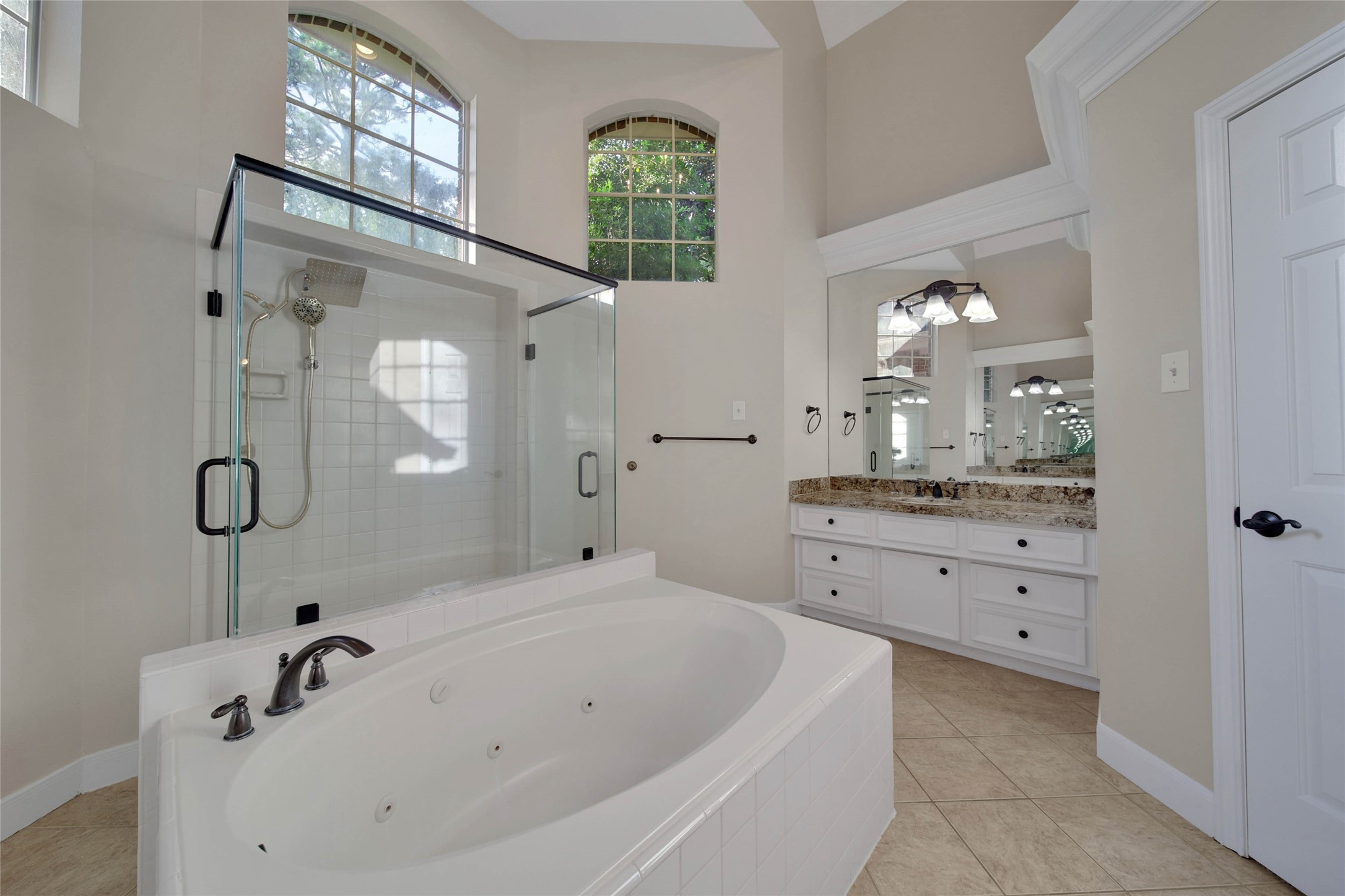 Separate whirlpool tub huge oversize shower with two doors, high ceilings and bright windows up high, separate vanities and lots of storage make this a fabulous bathroom.