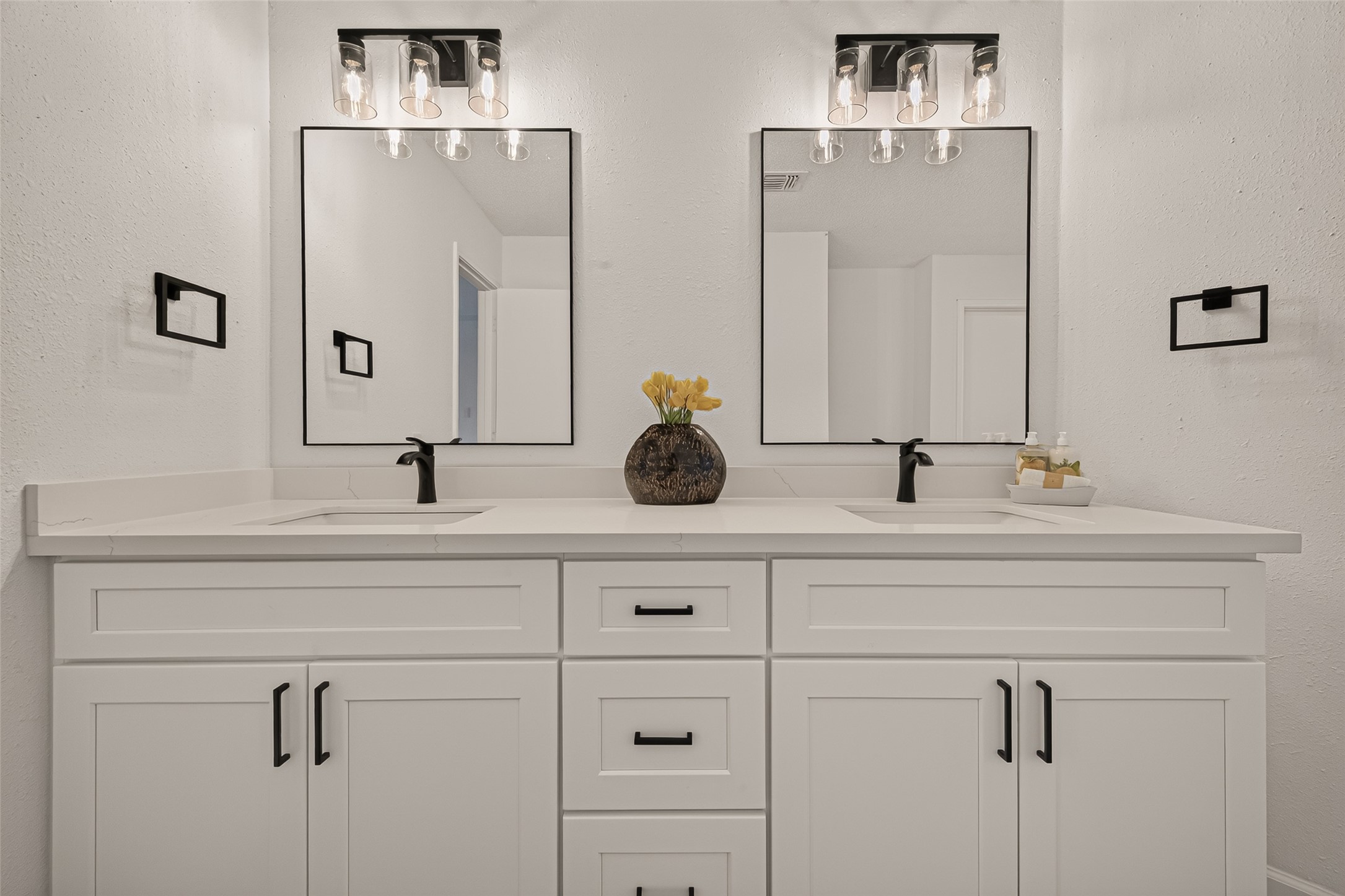 Double vanity with sleek black fixtures and modern mirrors.