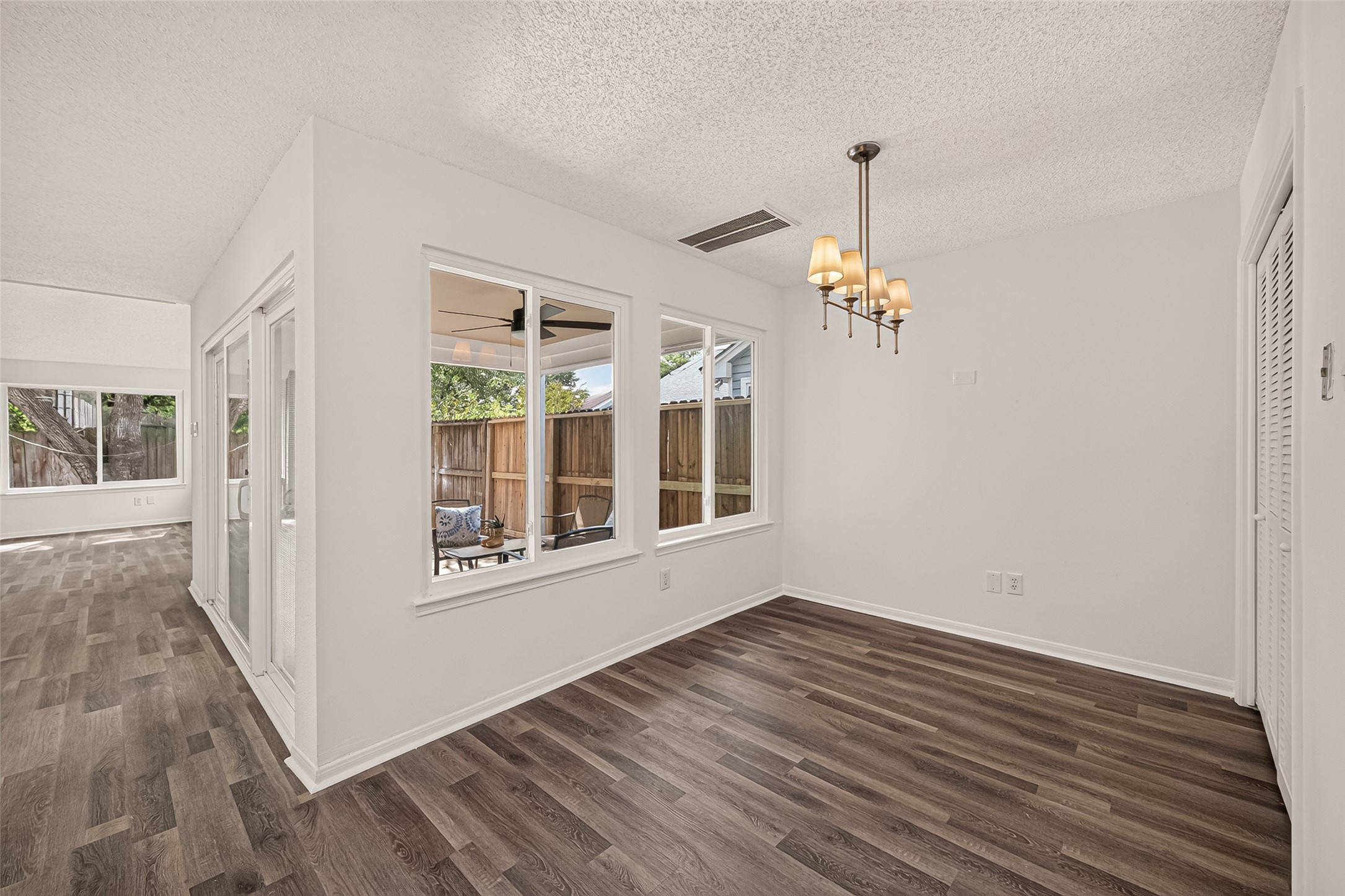 Bright breakfast area with modern chandelier and large windows offering a view of the cover patio.