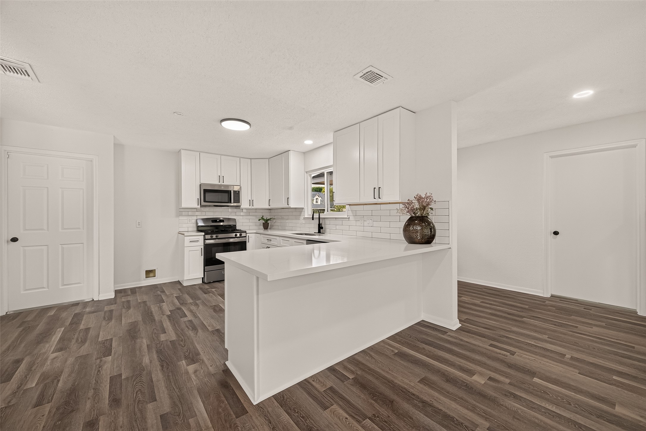 Sleek and modern kitchen featuring crisp white cabinetry, stainless steel appliances, and a spacious peninsula with elegant countertops