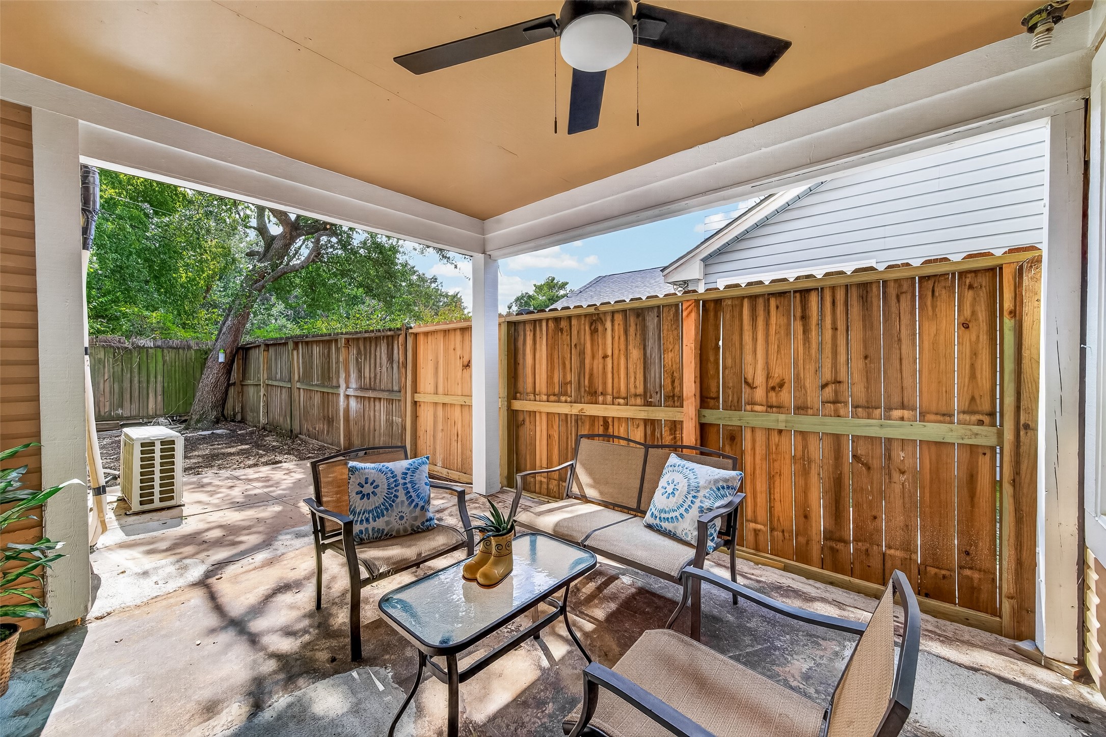 Charming, covered patio with cozy seating and ceiling fan, perfect for relaxing or entertaining.