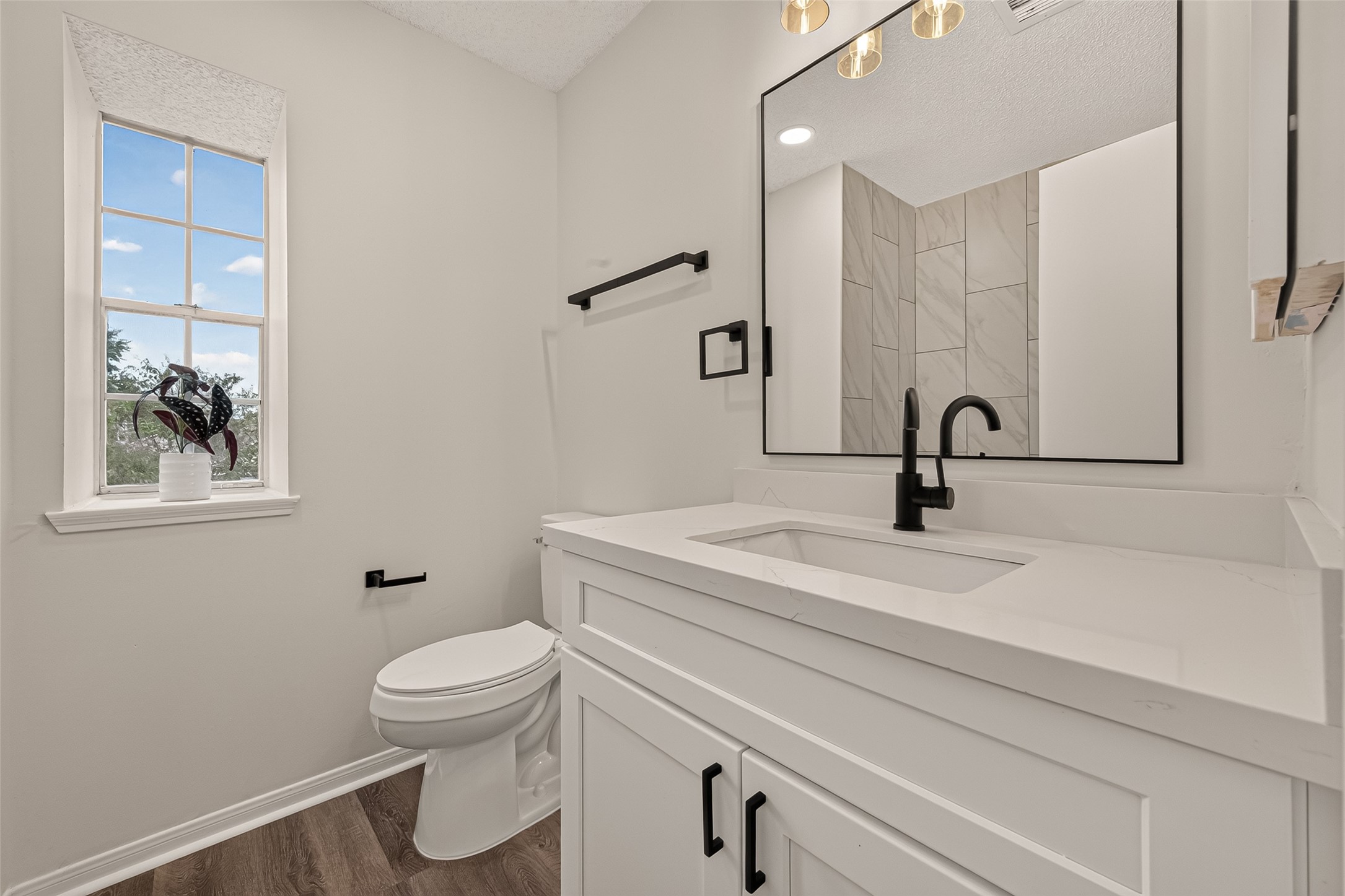 Bright and modern secondary bathroom upstairs featuring sleek fixtures, a large mirror, and a window offering natural light.