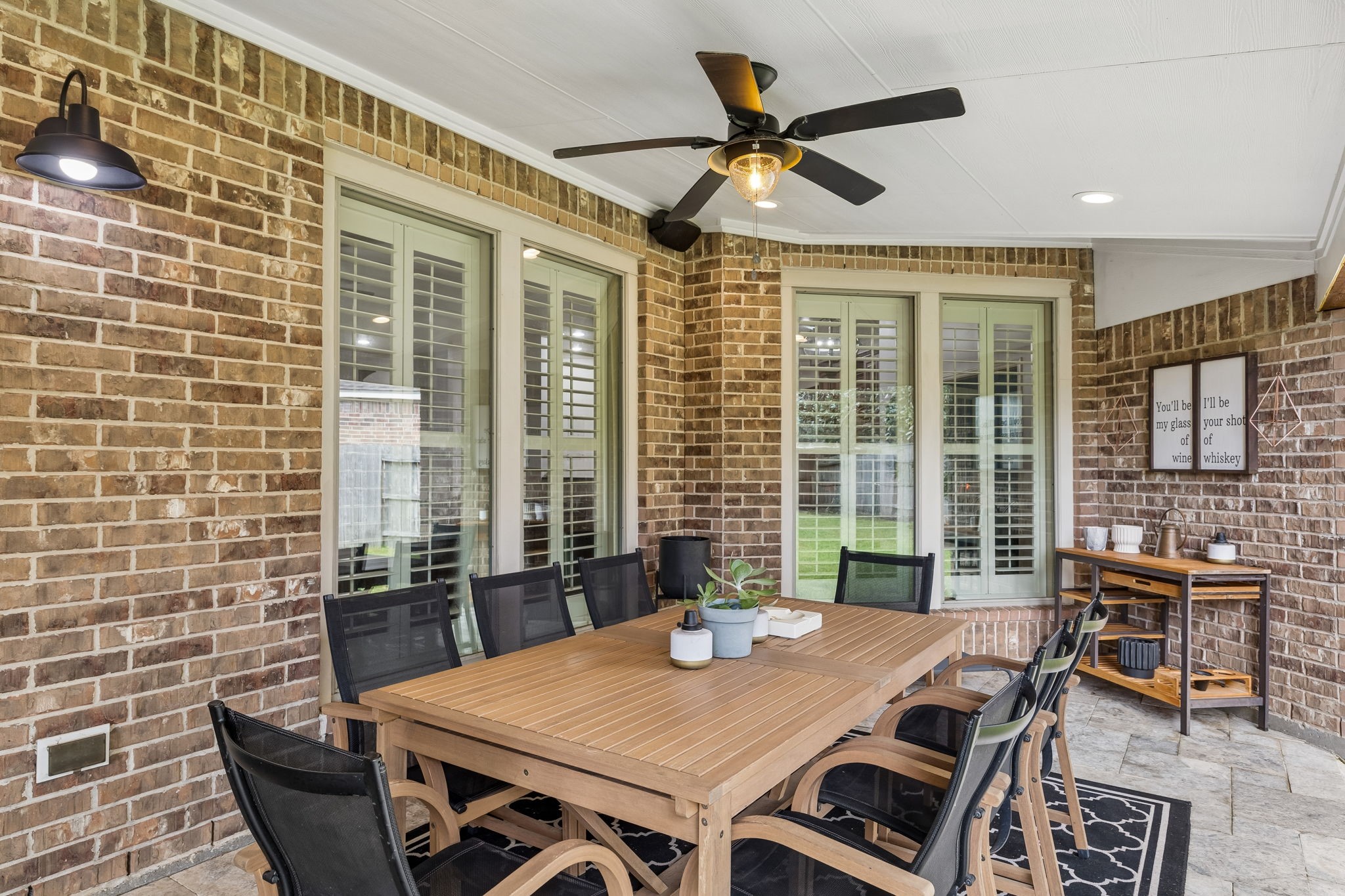 Covered outdoor living area with ceiling fan and a comfortable setup overlooking the backyard.