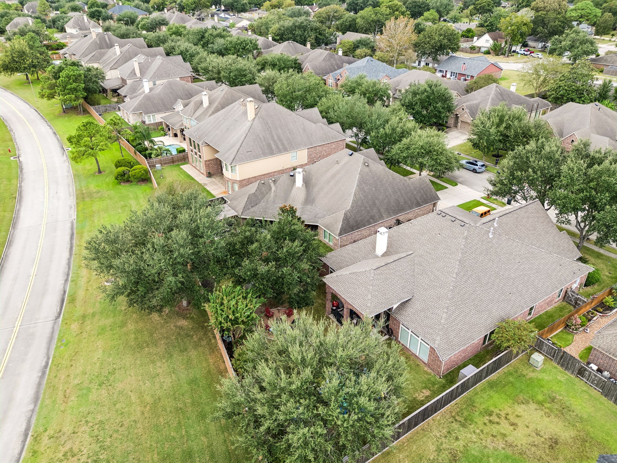 Aerial view showing the home, lot, mature landscaping, and surrounding neighborhood setting.