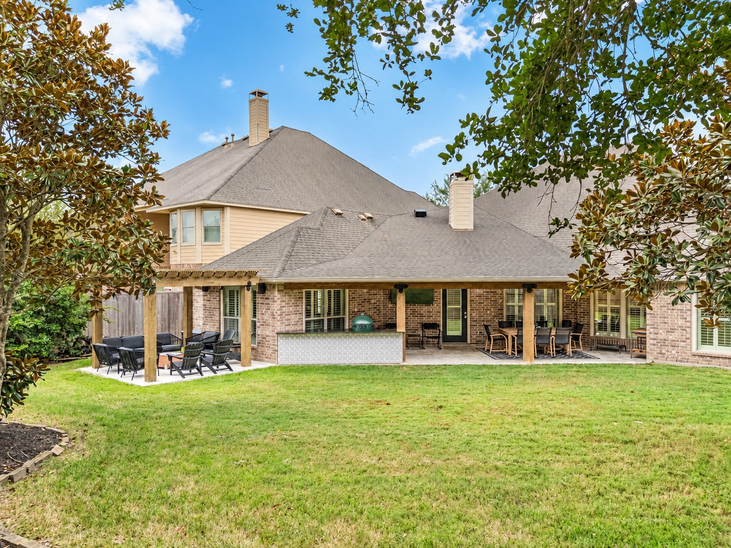 Rear exterior view showcasing the home, covered patio, and open backyard.