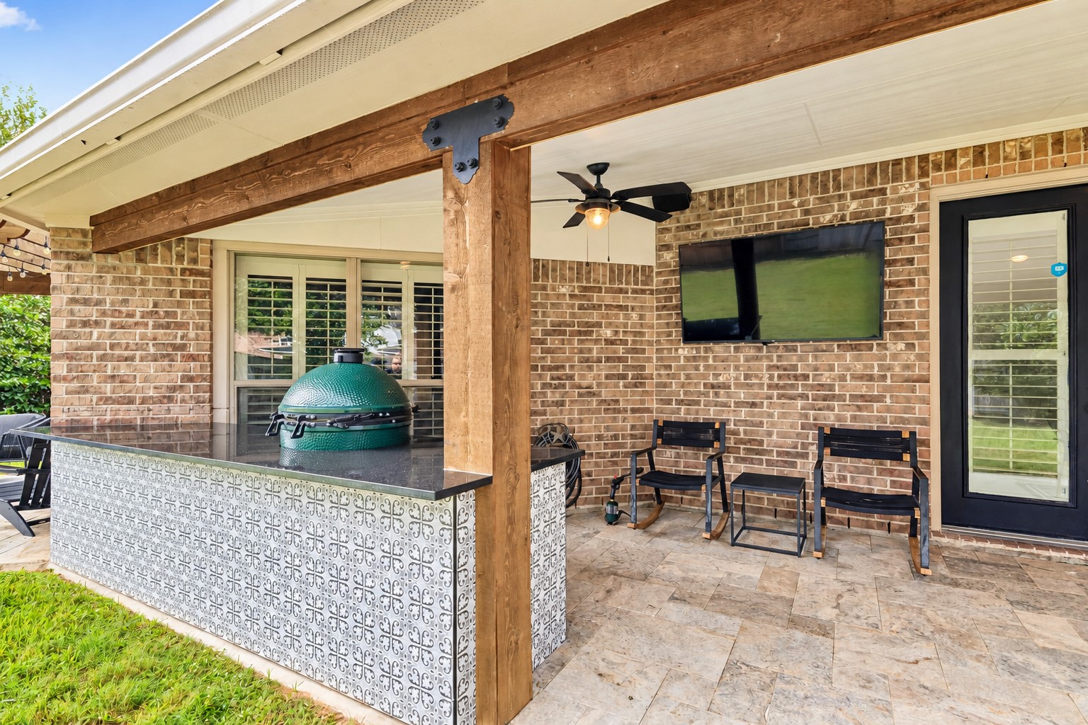Spacious covered patio with brick exterior, ceiling fan, and room for entertaining.