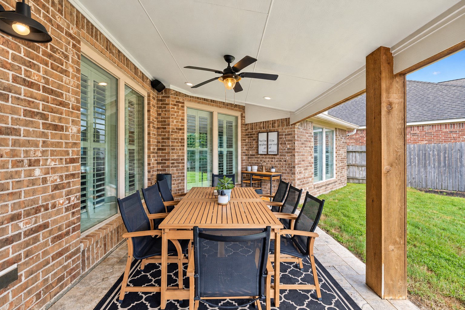 Covered patio with ceiling fan and ample space for outdoor dining, relaxing, or entertaining.