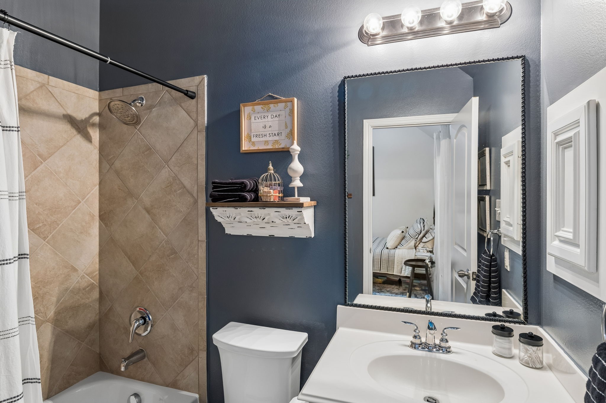 Full bathroom with vanity, large mirror, tub/shower combination, and updated finishes.