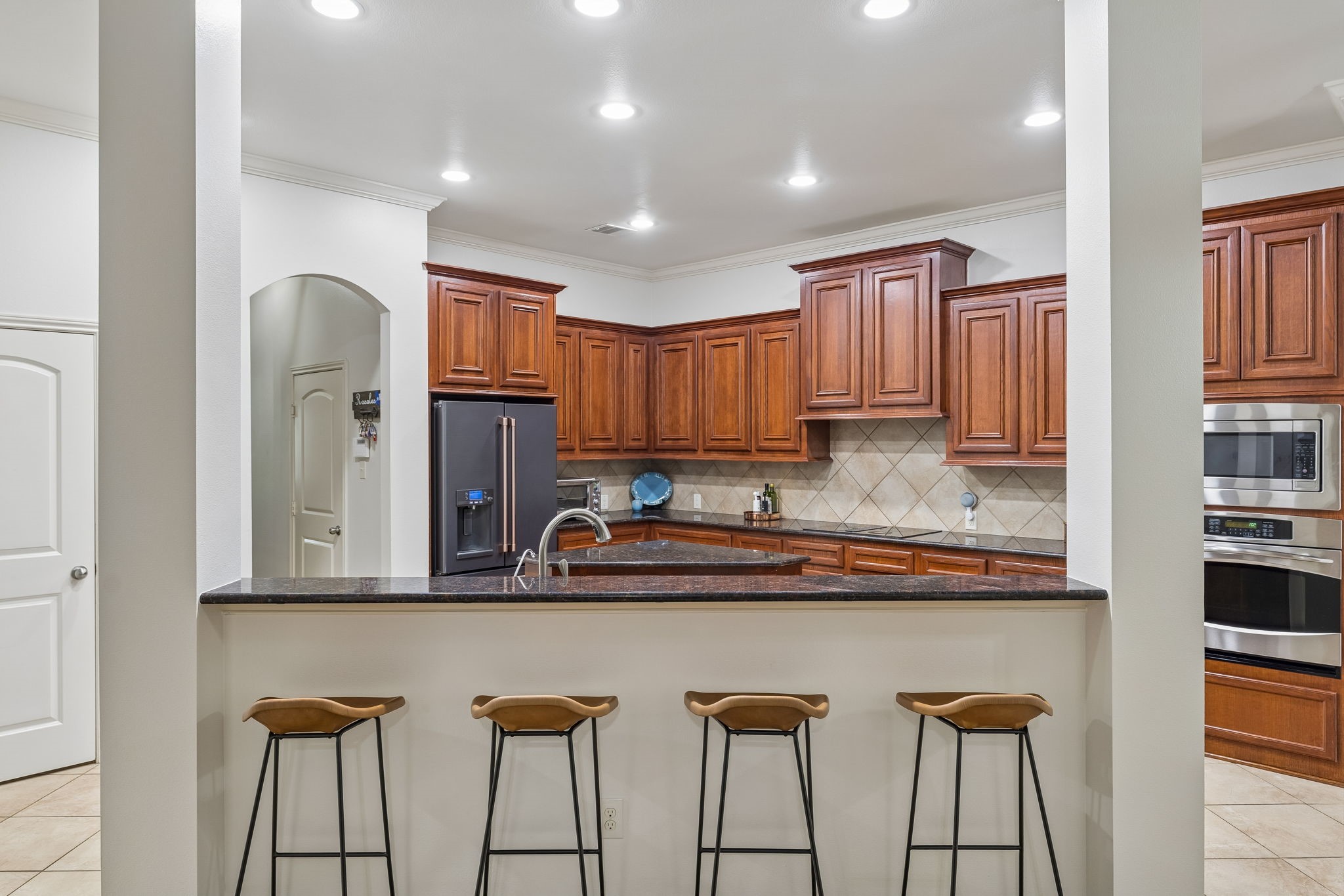 Spacious kitchen with rich wood cabinetry, granite countertops, stainless steel appliances, and breakfast bar seating.