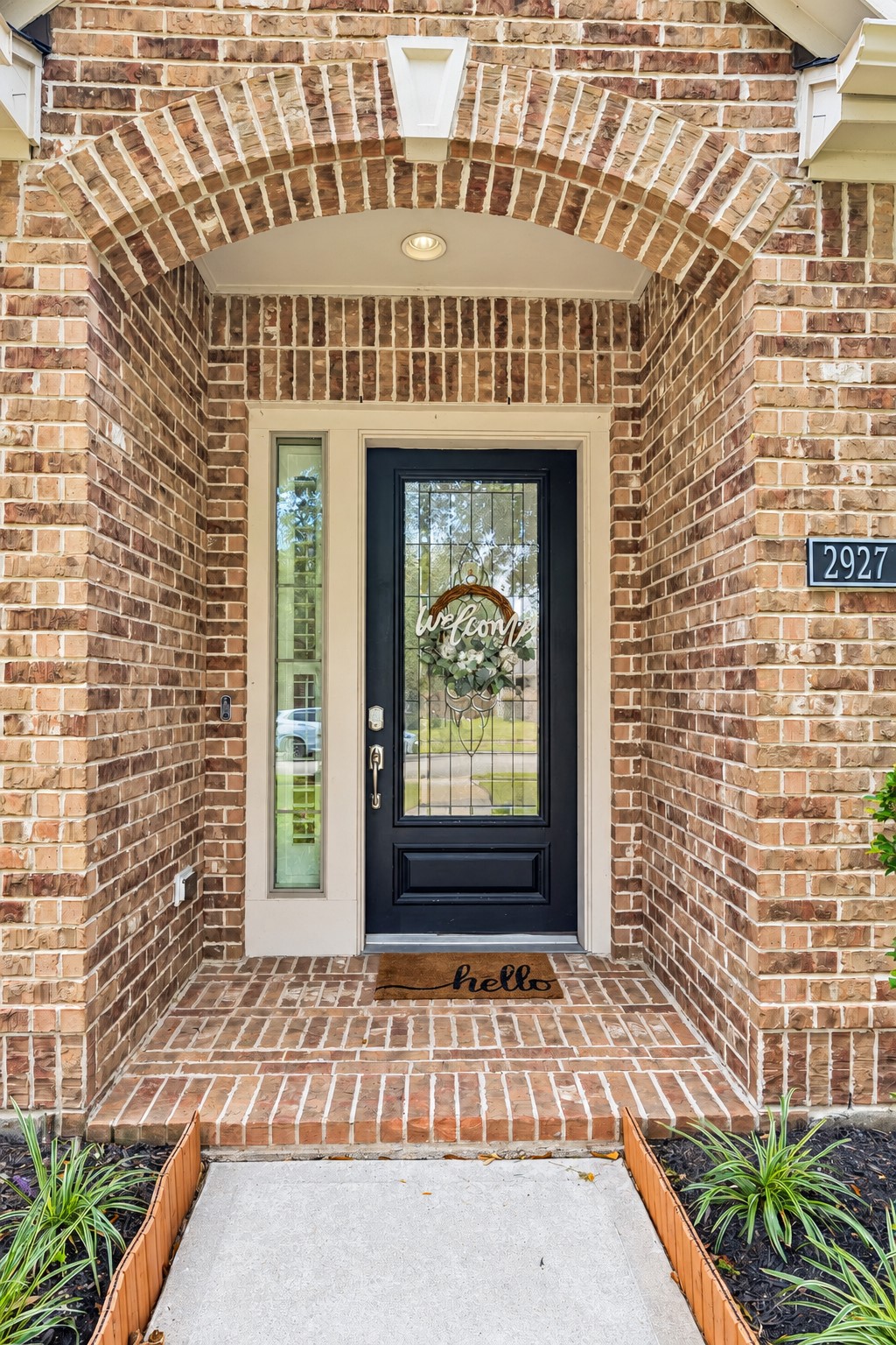 Close-up of the front entry featuring brick detailing and a distinctive glass-paneled front door.
