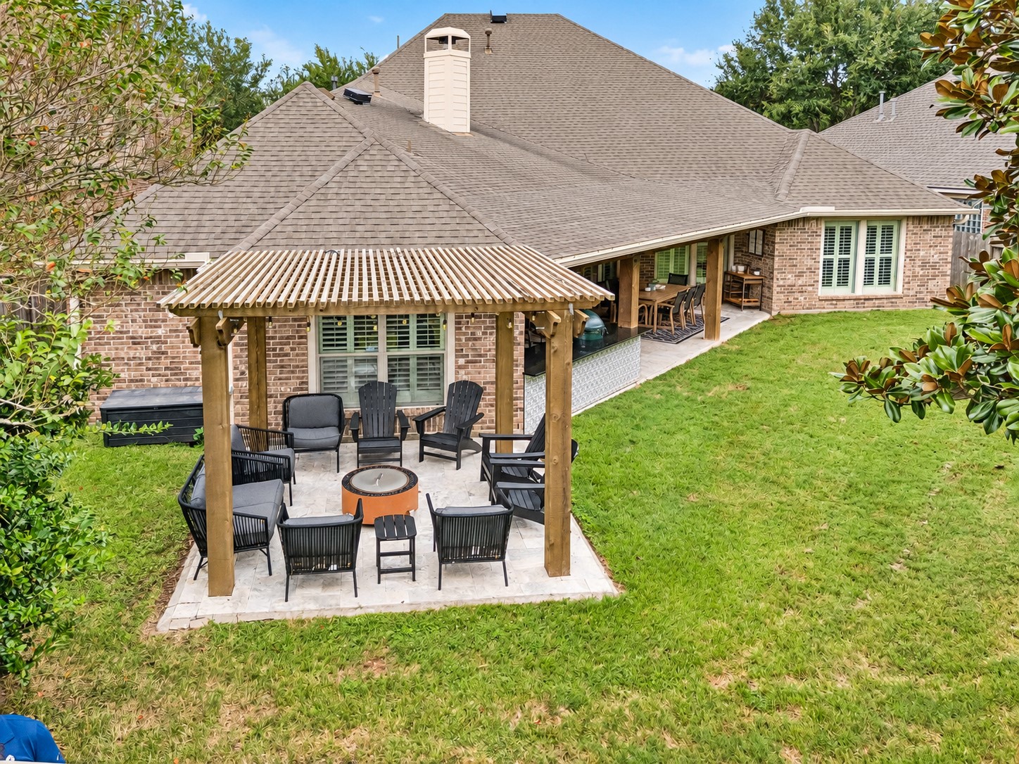 Elevated rear view highlighting the covered outdoor living area and expansive lawn.