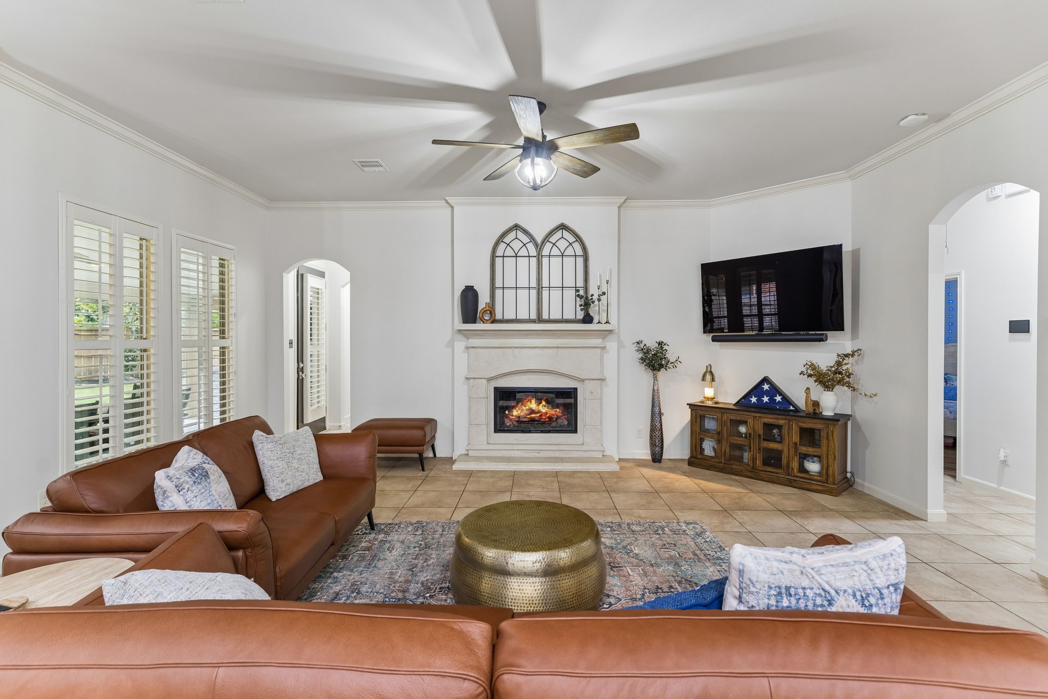 Spacious living area with fireplace, ceiling fan, abundant natural light, and an inviting open layout.