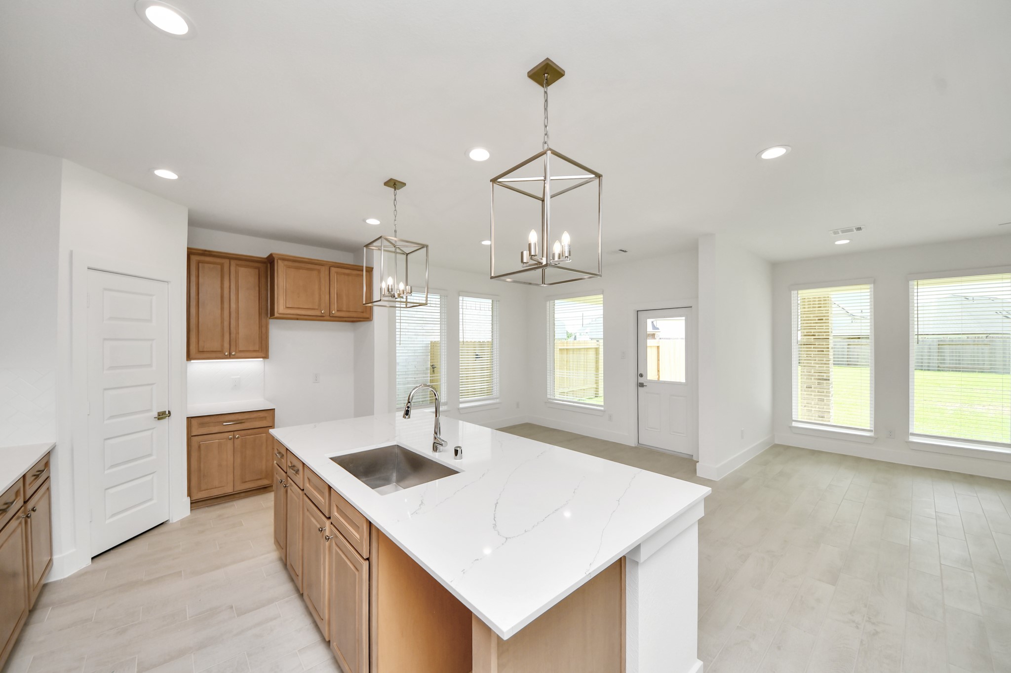 This kitchen is truly a chef's dream! This haven Boasts high ceilings, recessed & pendant lighting, stained wood cabinets, granite countertops, stainless steel appliances, a modern tile backsplash.  All of this overlooks your expansive family room, creating a perfect space for culinary delights and family gatherings. Sample photo of completed home with similar floor plan. Actual colors and selections may vary.