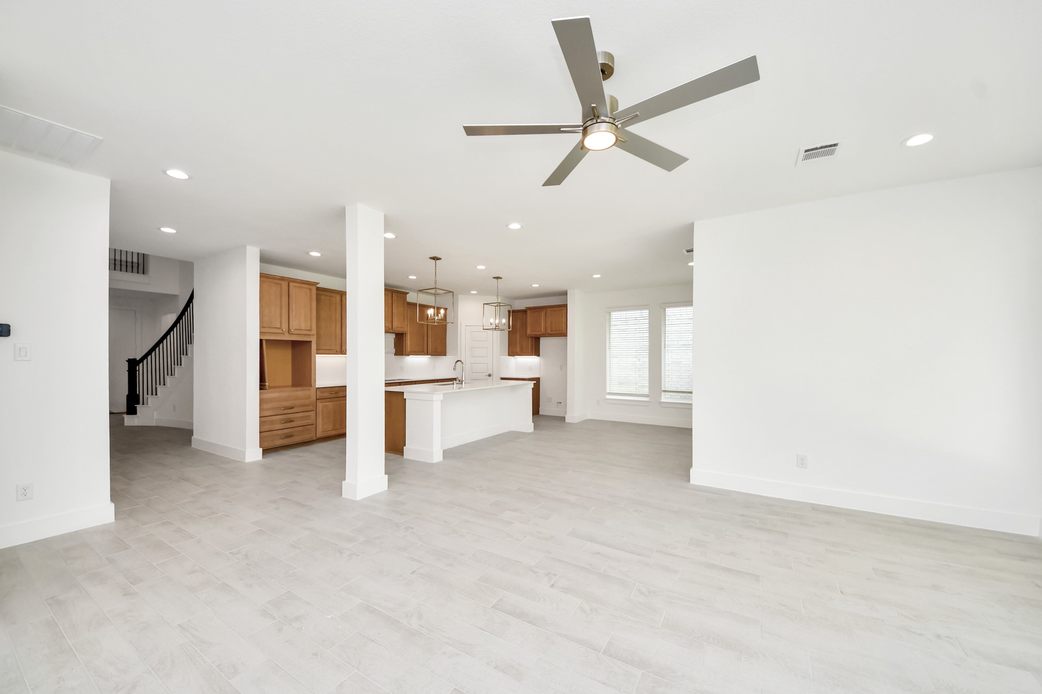 Family room flooded with natural light through the expansive windows.  The premium tile flooring adds a touch of luxury to the space, creating the perfect setting for relaxing moments and cherished gatherings with loved ones. Sample photo of completed home with similar floor plan. Actual colors and selections may vary.