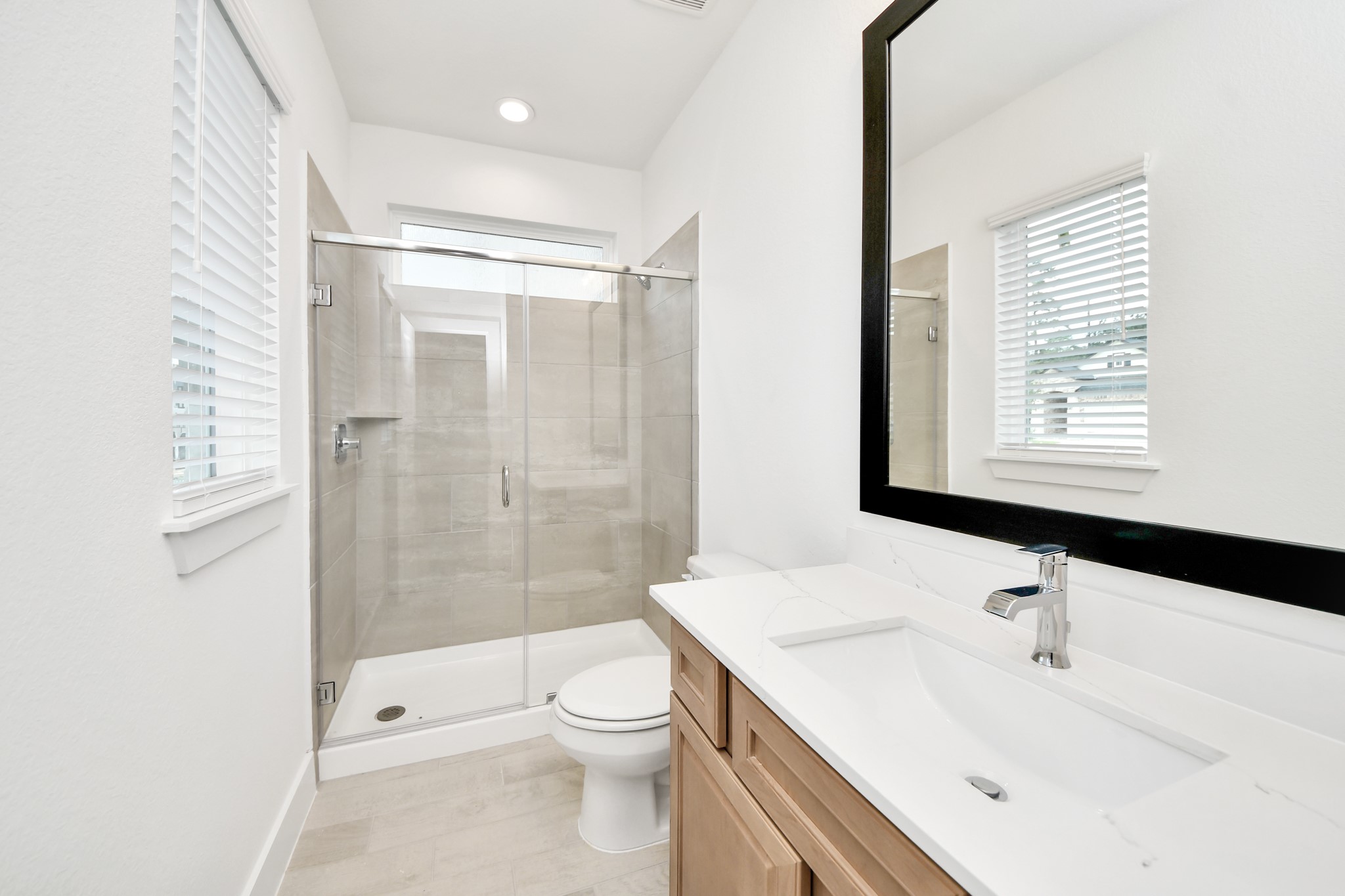 Secondary bath features tile flooring, walk-in shower with tile surround, light stained wood cabinets, beautiful light countertop. Sample photo of completed home with similar floor plan. Actual colors and selections may vary. Secondary bath features tile flooring, walk-in shower with tile surround, light stained wood cabinets, beautiful light countertop. Sample photo of completed home with similar floor plan. Actual colors and selections may vary.