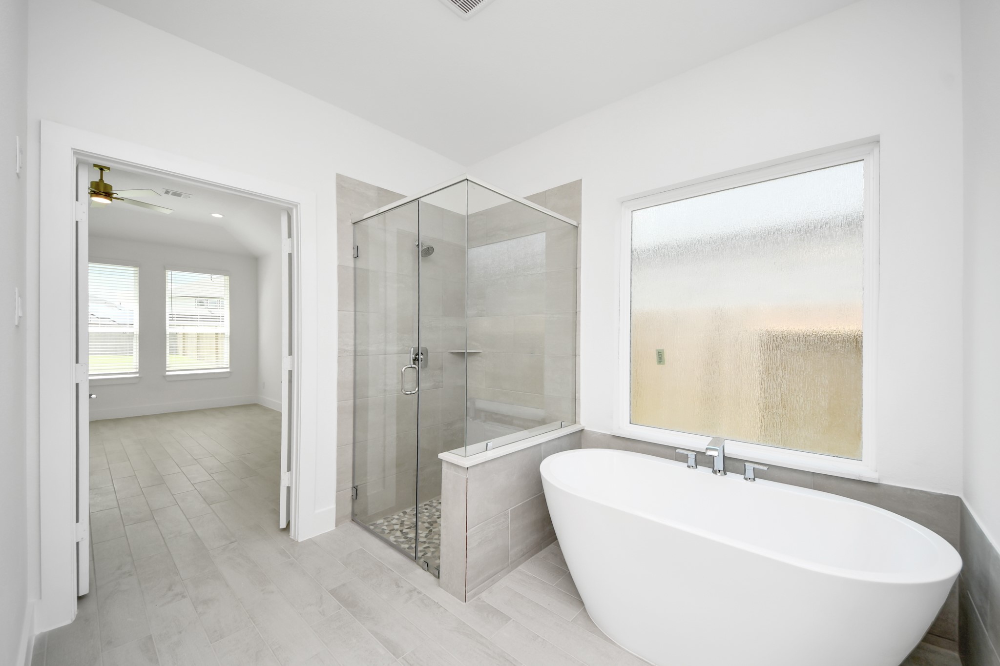 Indulge in a spa-like retreat within the confines of this primary bathroom. Delight in a spacious walk-in shower enveloped in stylish tile surround, unwind in a separate garden tub adorned with custom detailing. Sample photo of completed home with similar floor plan. Actual colors and selections may vary.