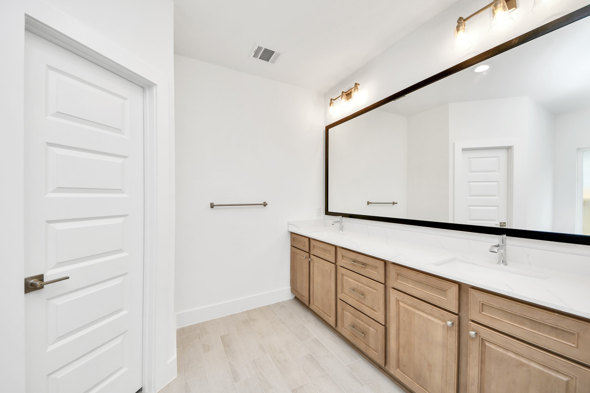 Elevate your daily routine at the elegant vanity, now equipped with double sinks, light countertops, modern hardware, and beautiful vanity lights. Sample photo of completed home with similar floor plan. Actual colors and selections may vary.