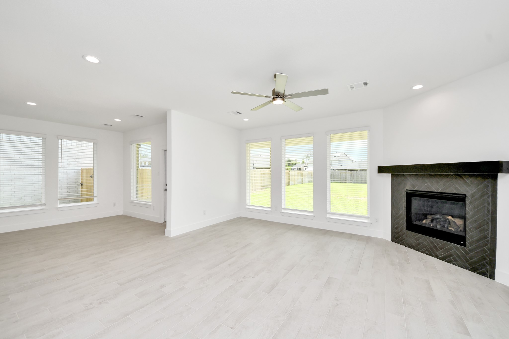 Bring your loved ones and guests together in the inviting living room! Boasting lofty high ceilings, recessed lighting, a stylish ceiling fan, custom paint, stunning flooring, and expansive windows that flood the space with ample natural light all day long. Sample photo of completed home with similar floor plan. Actual colors and selections may vary.
