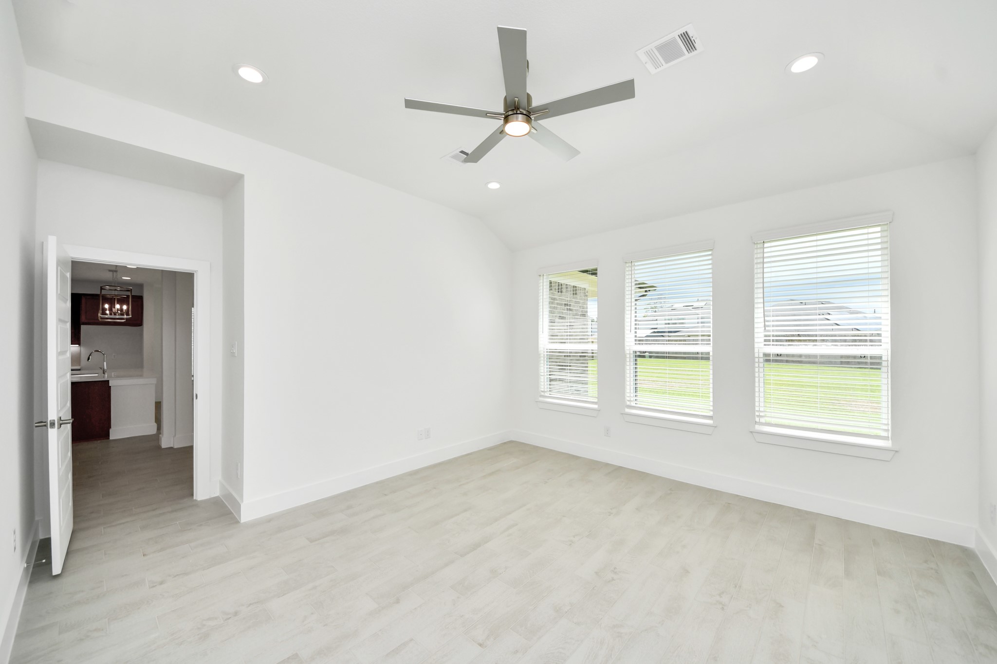 Escape and relax in the exquisite primary suite, a haven to unwind after a long day. The spacious room, located on first floor, soothing paint tones, high ceilings, and expansive windows adorned with privacy blinds. Sample photo of completed home with similar floor plan. Actual colors and selections may vary.