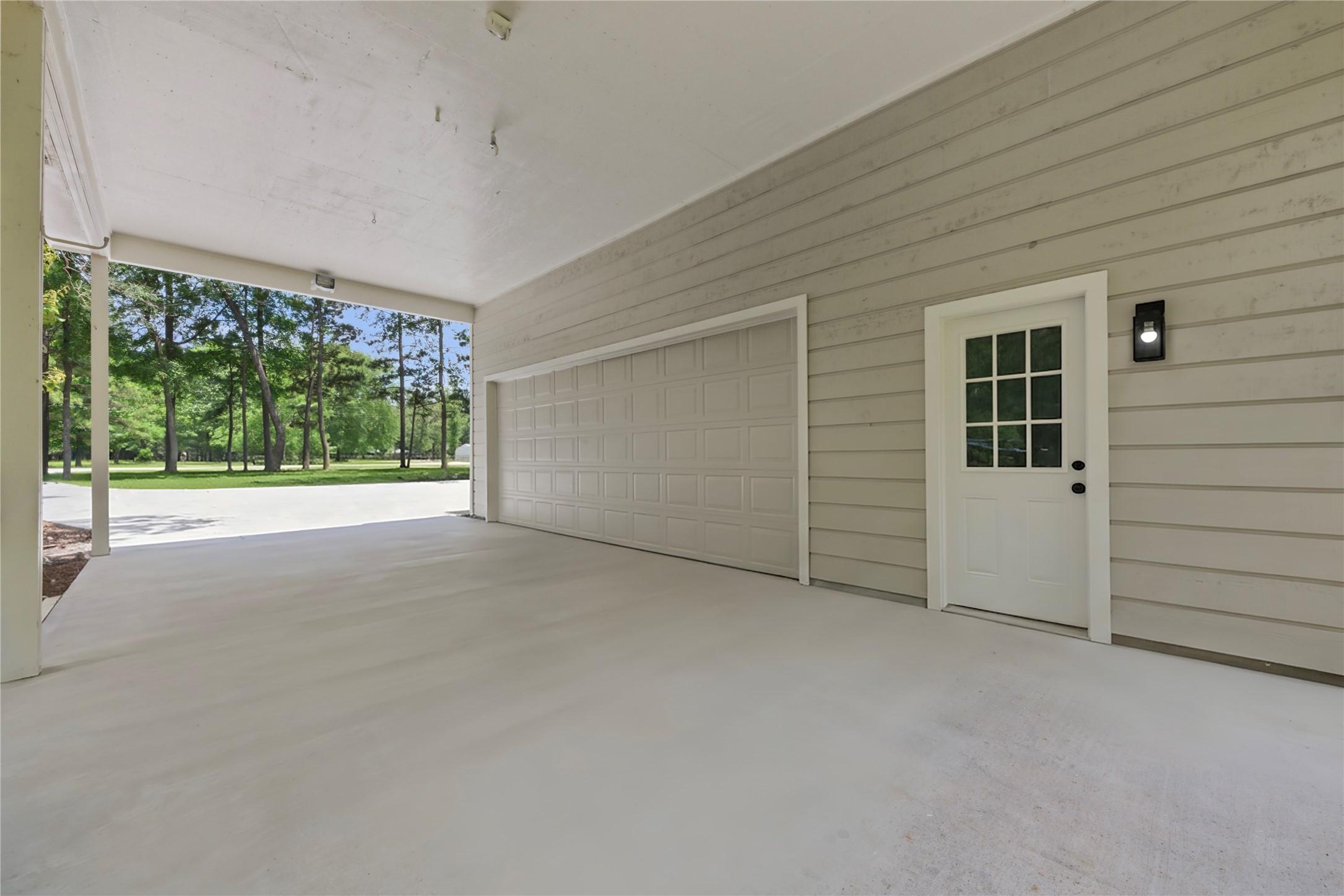 Covered drive-through area connecting the main home to the detached garage structure. Side-entry door access leads to the detached building's flex space. Sheltered access in all weather.