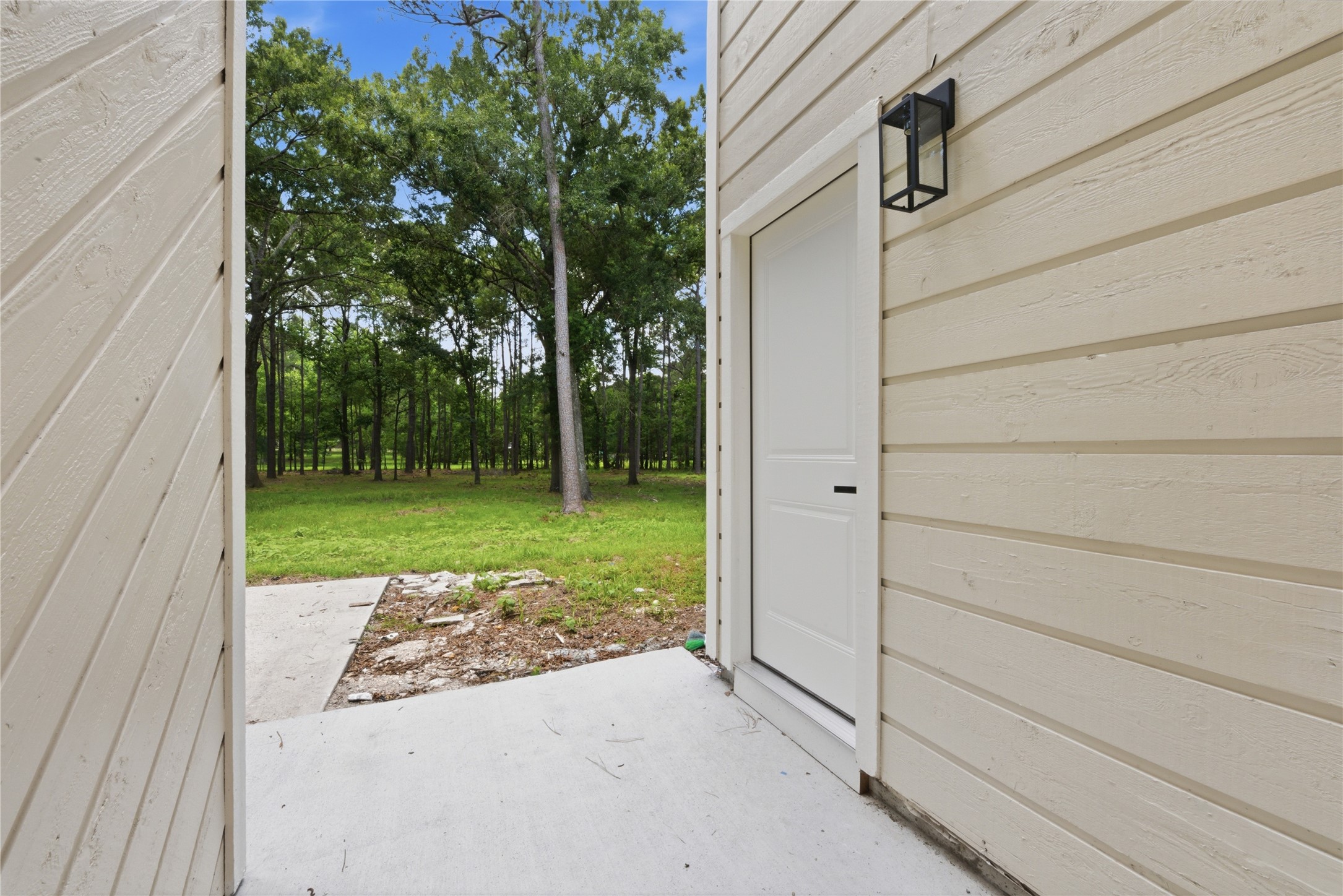 Private side entrance to the detached structure with designer black exterior sconce, board-and-batten siding, and walk-out access to the 1.67-acre wooded lot.