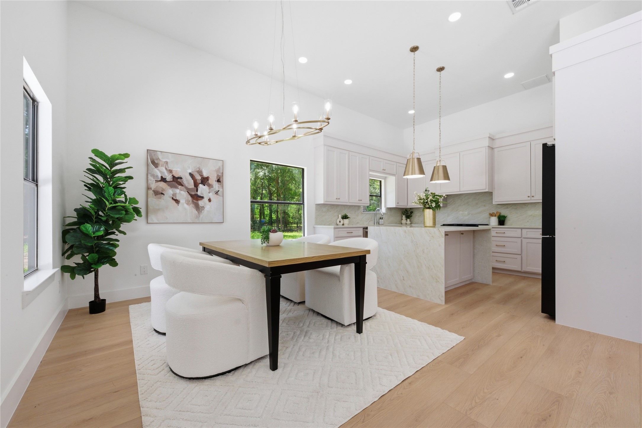 Designer chef's kitchen featuring waterfall quartz island, custom soft-close cabinetry, quartz countertops, brass pendant lighting, statement chandelier, gas range, and walk-in pantry. Refrigerator included.